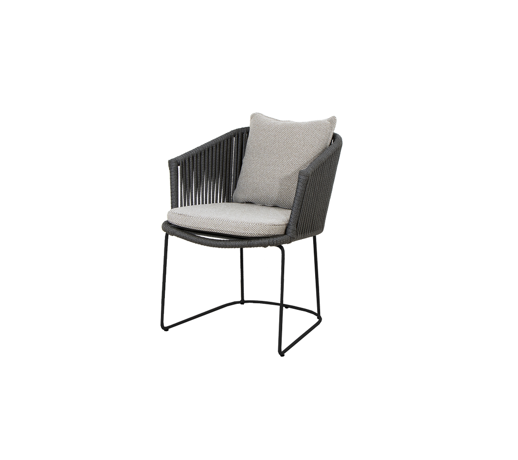 En modern stol med korgdesign och ett mjukt kudde, som har en slank metallbas för stöd.