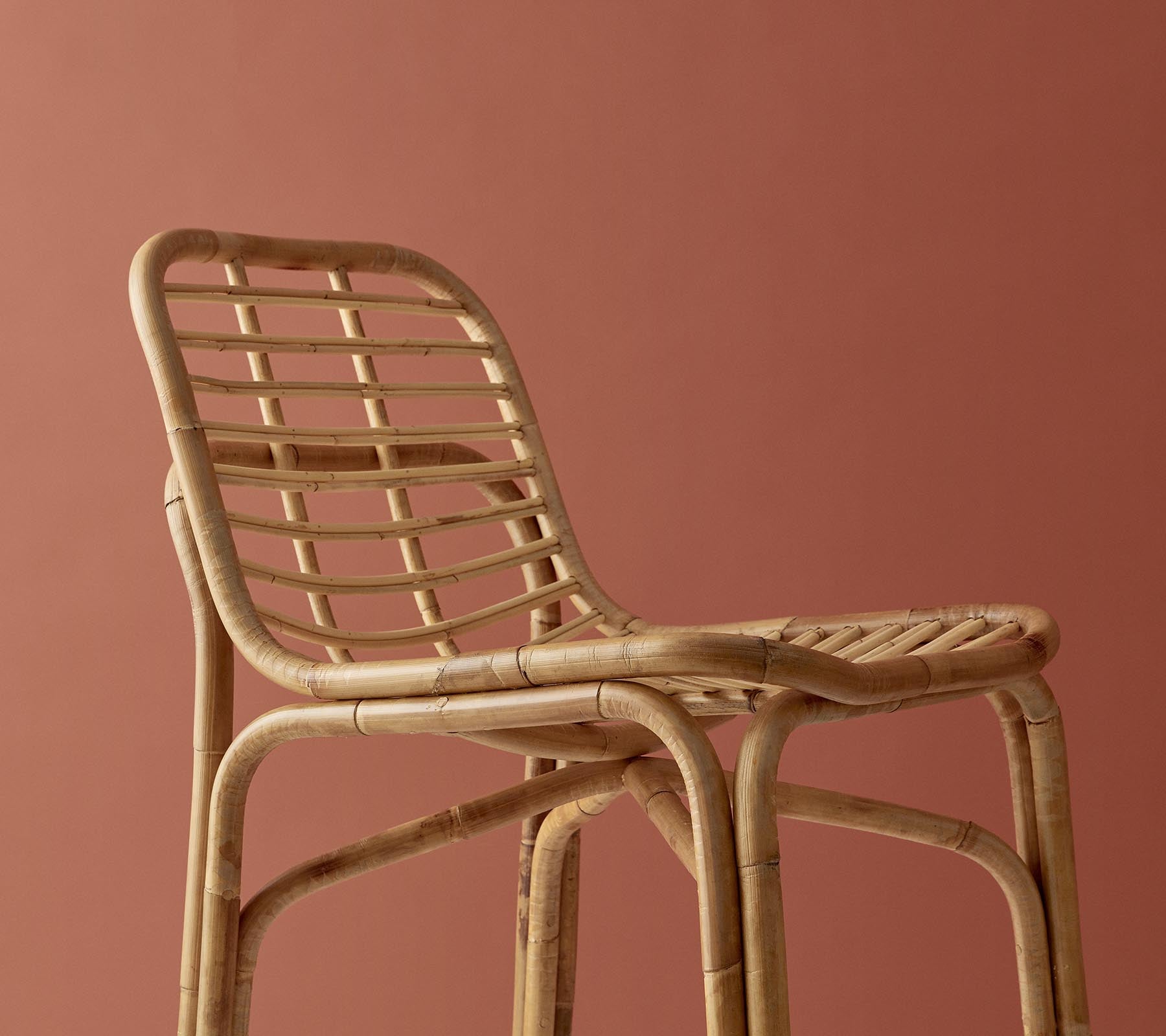 Stilig vävd stol i en naturlig finish med en minimalistisk design mot en dämpad bakgrund.