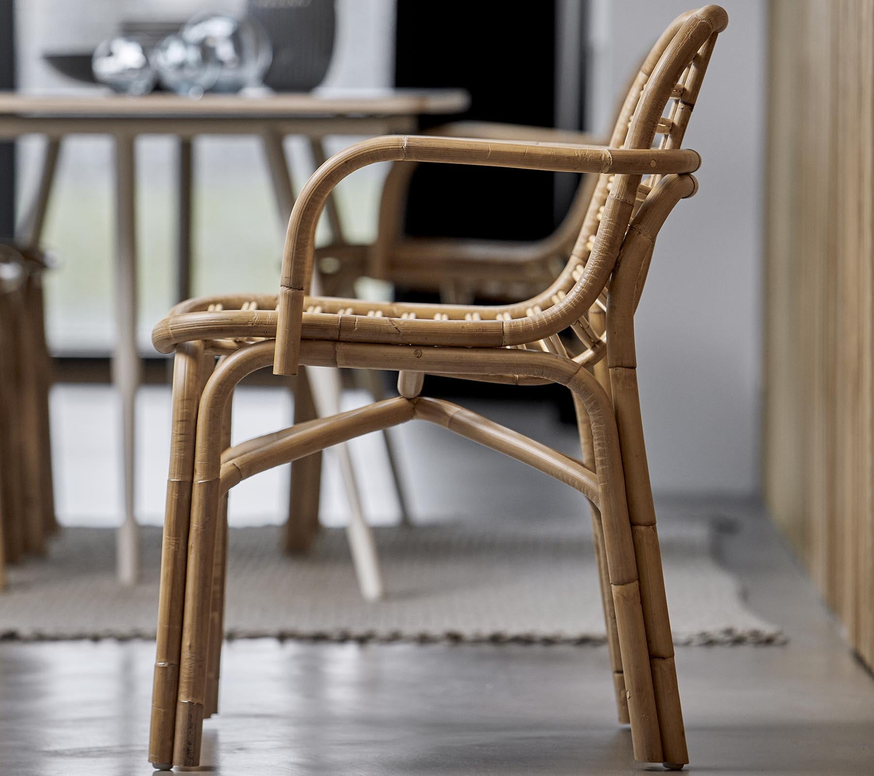 En stilren stol av naturliga materialer, med en vävd design och armstöd, lämplig för olika inredningsmiljöer.