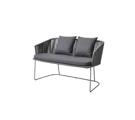 Tvåsitssoffa med en stilren design, som har en vävd sits och mjuka kuddar i en mörk färgskala.