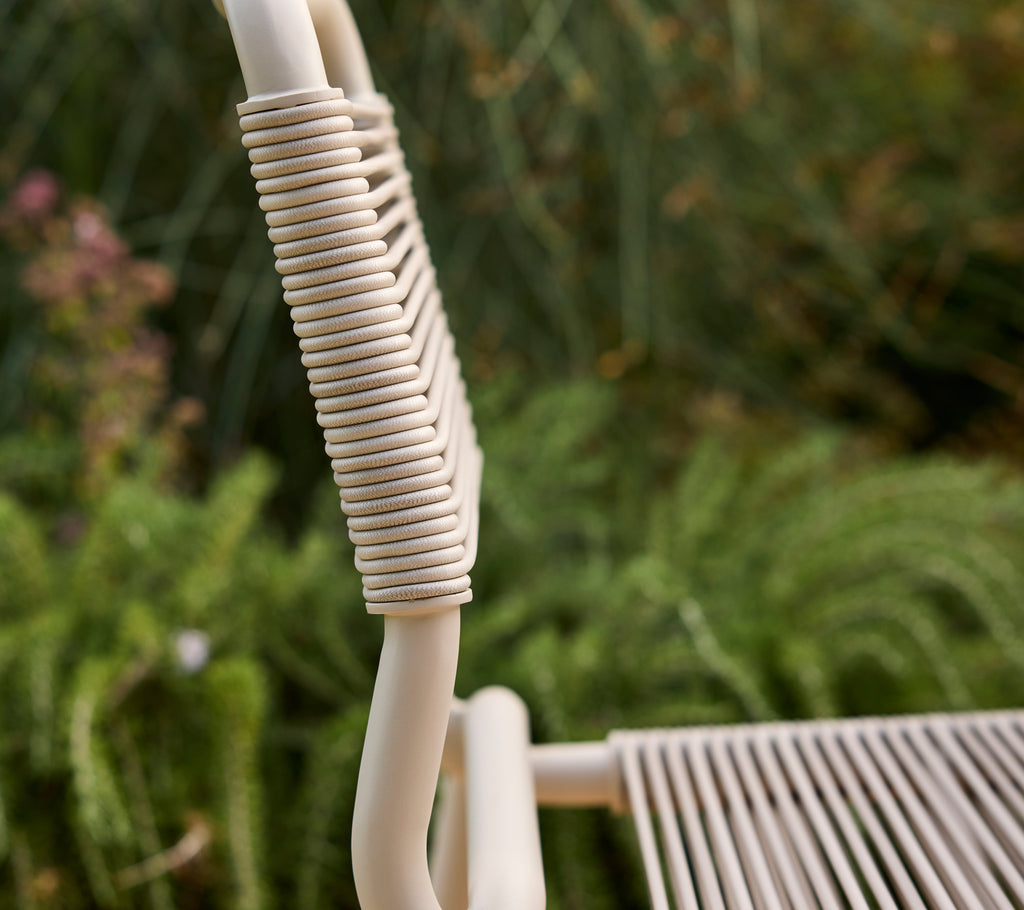 Beige stol delvis synlig med en suddig grön bakgrund.