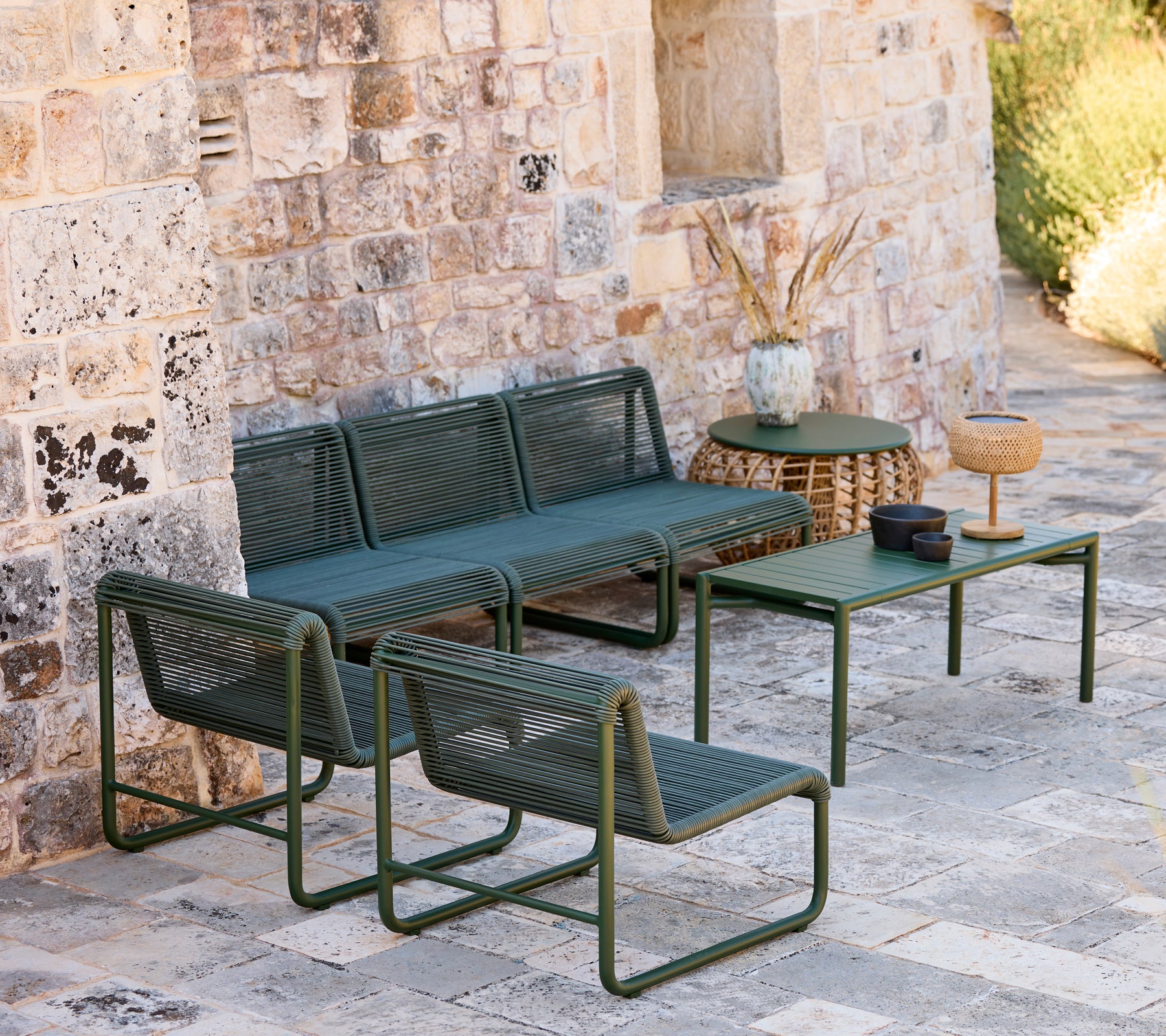 Modern grön soffa och stolar med ett matchande bord i en avslappnad loungeinställning.