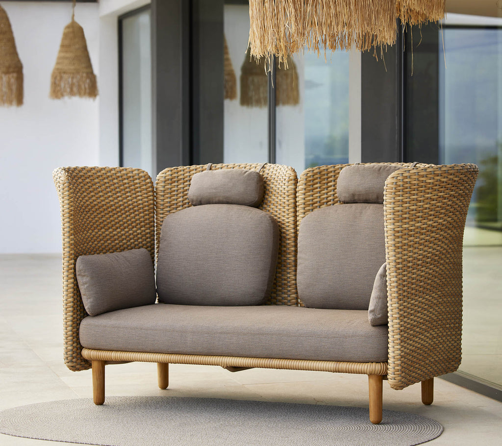 En stilren loungesoffa med vävda sidor och mjuka kuddar, designad för komfort och avkoppling. Idealisk för moderna utrymmen.