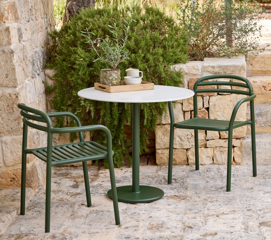 Moderna utomhusmiljö med gröna stolar och ett vitt bord.