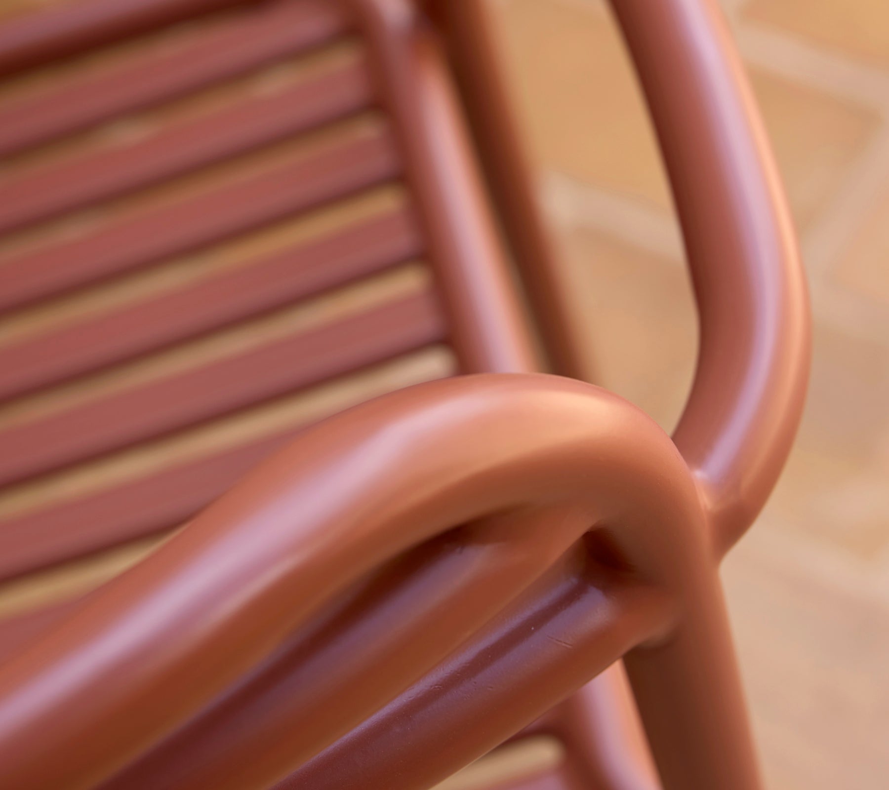 Närbild av en Bliss-fåtölj i en ökenröd nyans, som visar dess mjuka kurvor och lamelldesign.