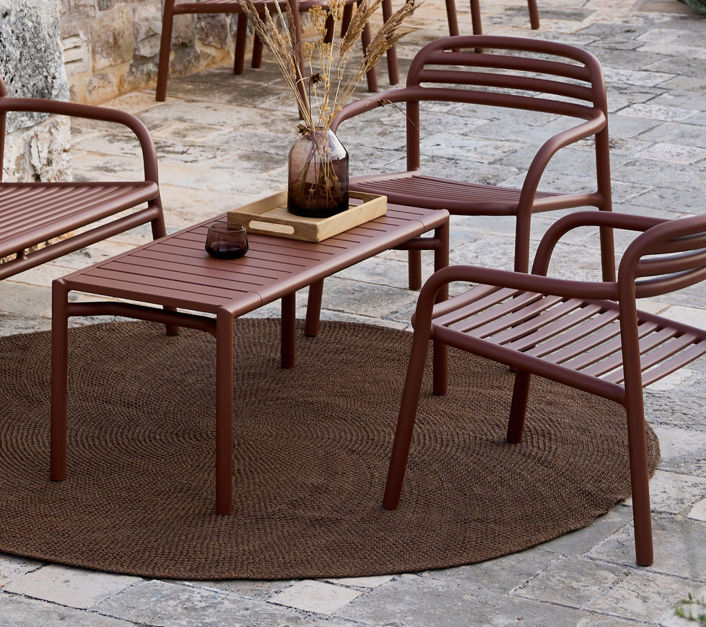 Minimalistiskt brunt bord och stolar arrangerade i en loungeinställning.