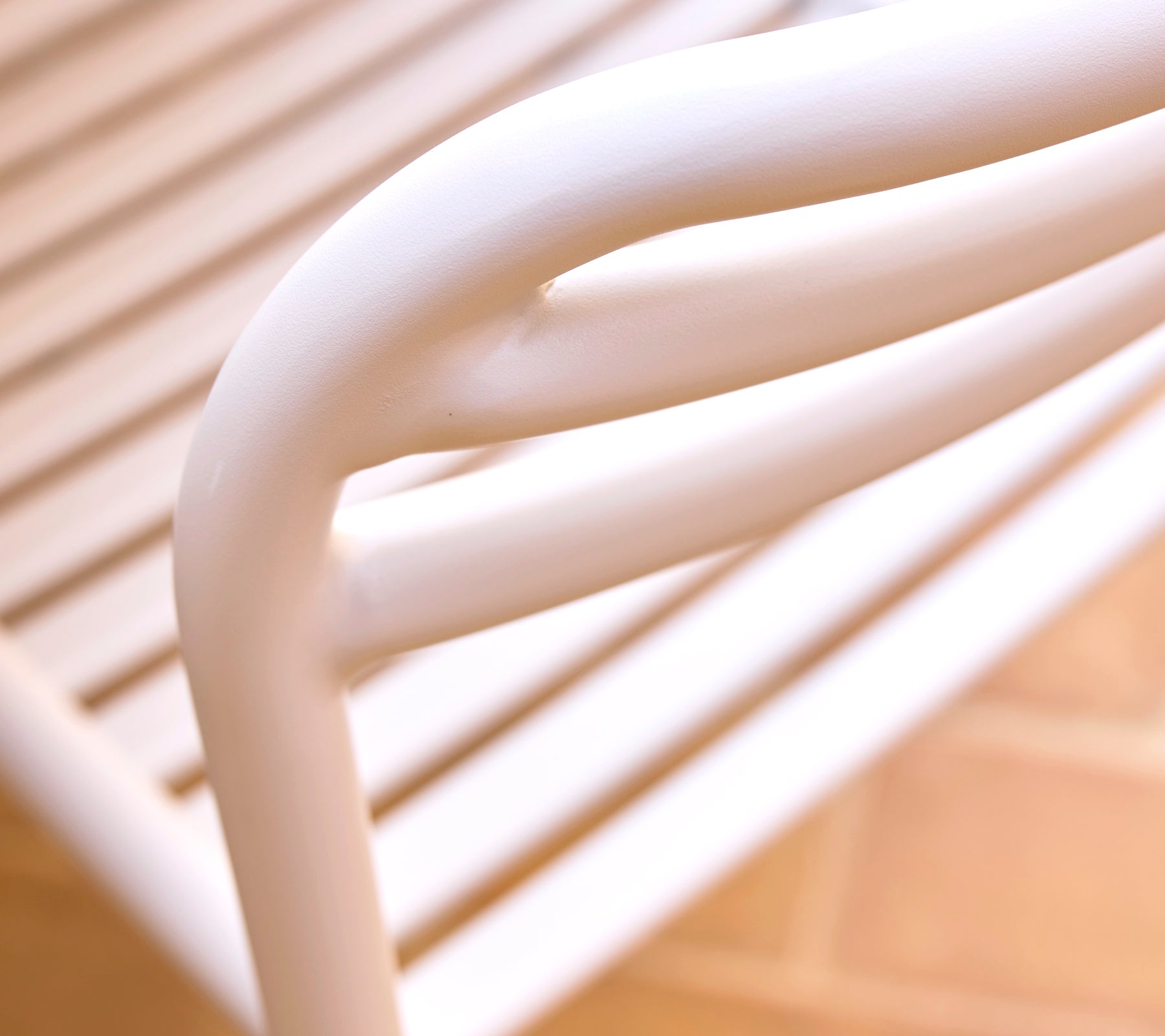 Närbild av en sandfärgad matstol som visar mjuka, böljande linjer och en elegant design som betonar modern stil och komfort.