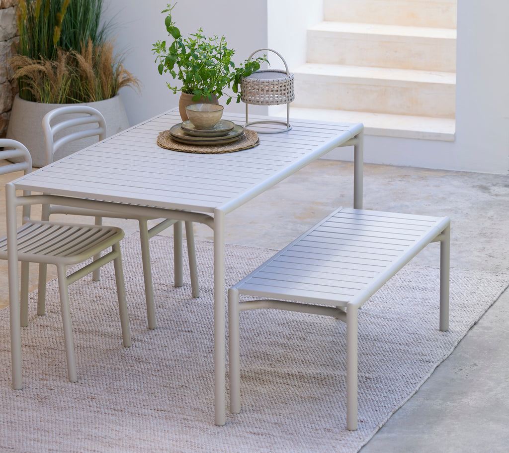 Moderna vita matbord med matchande bänk och stol i en minimalistisk miljö.