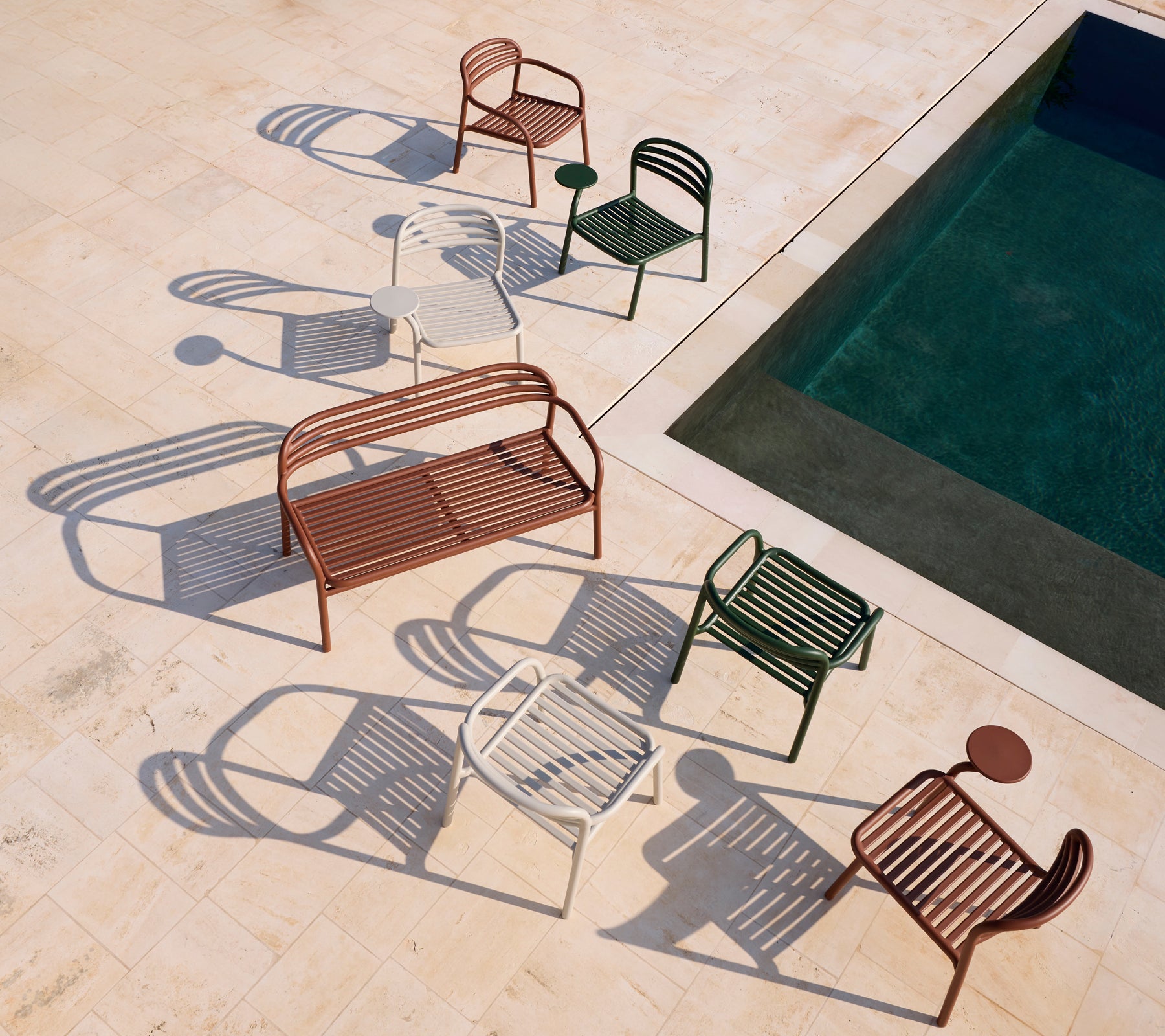 Set av moderna röda, vita, gröna stolar och en brun bänk nära en pool.