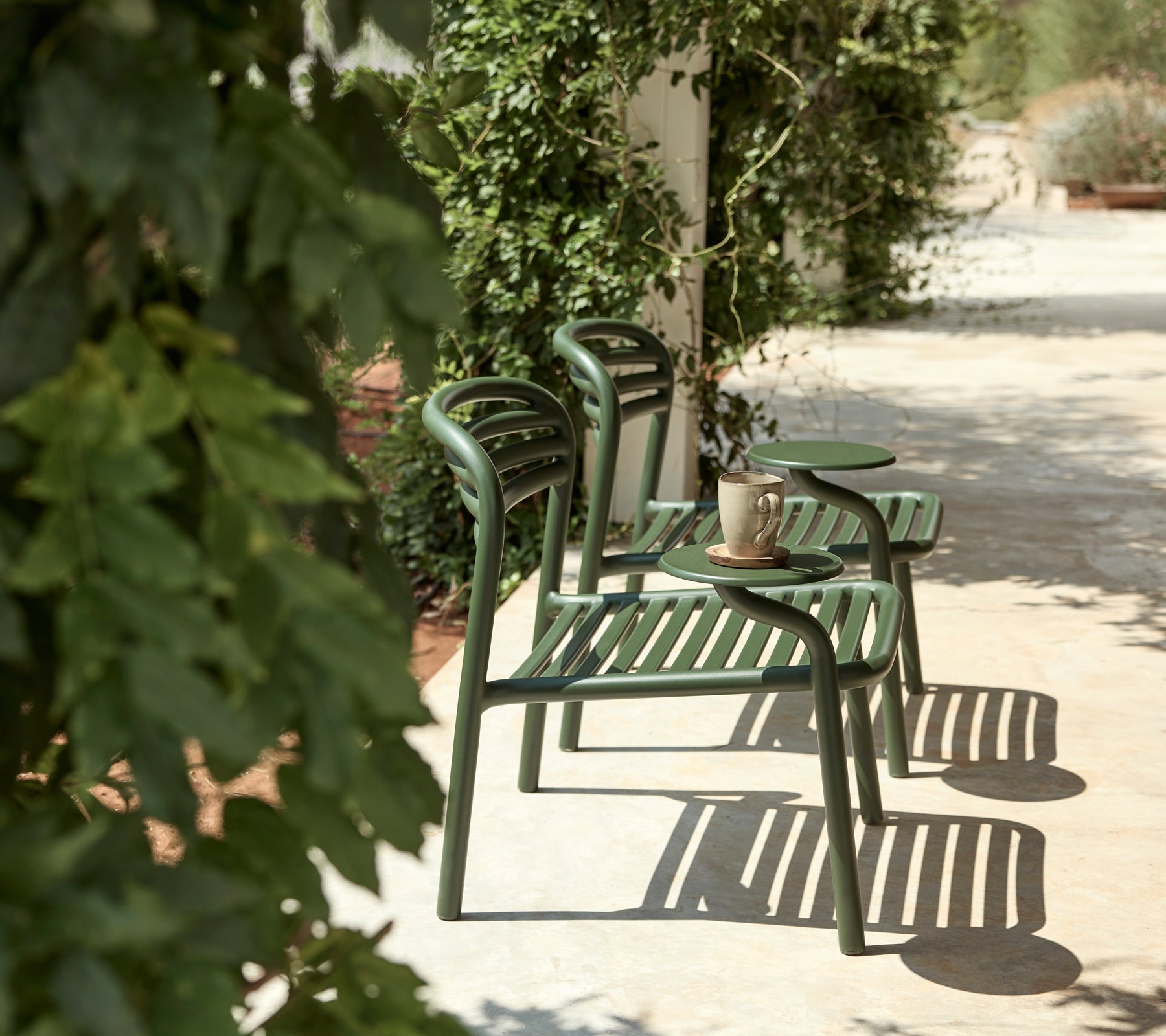 Gröna stolar och sidobord i en utomhusmiljö med frodig grönska.