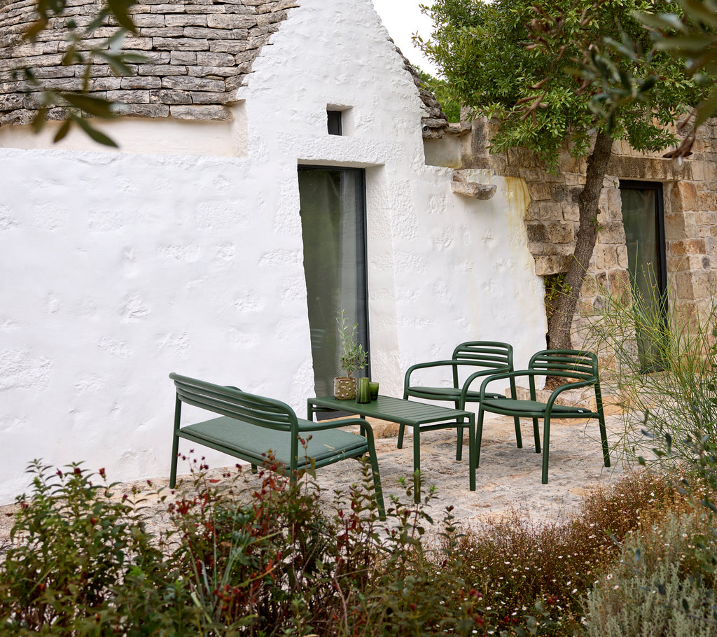 Grön utomhussoffa och fåtöljer med ett soffbord i en mysig miljö.