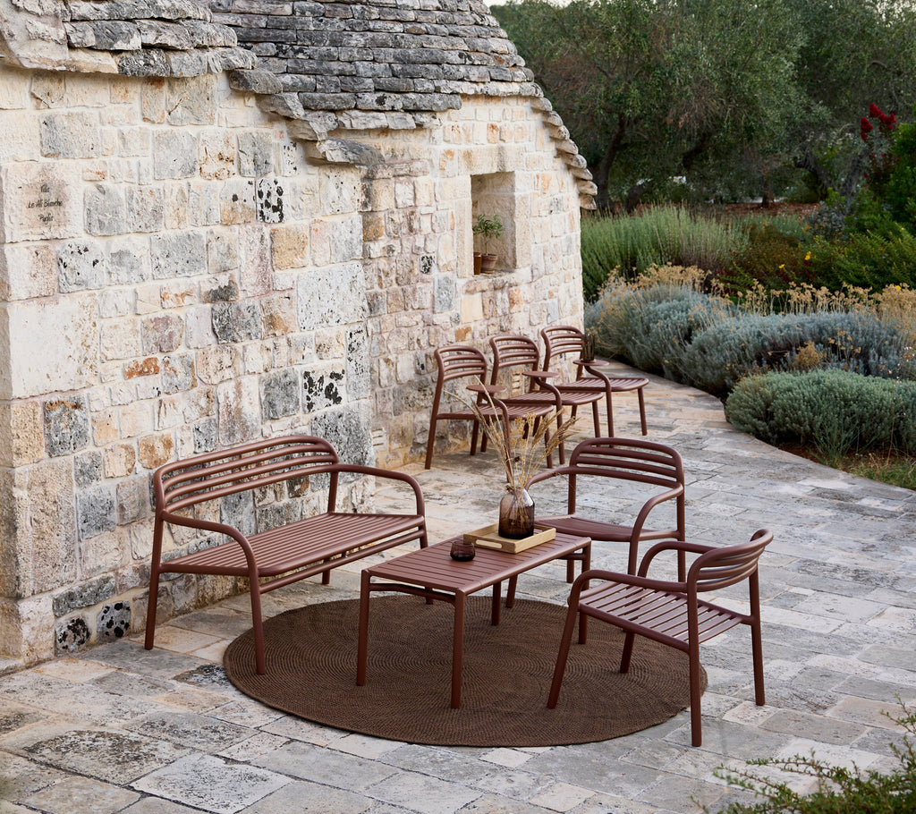 Brun utomhussoffa, stolar och bord i ett modernt loungeområde.