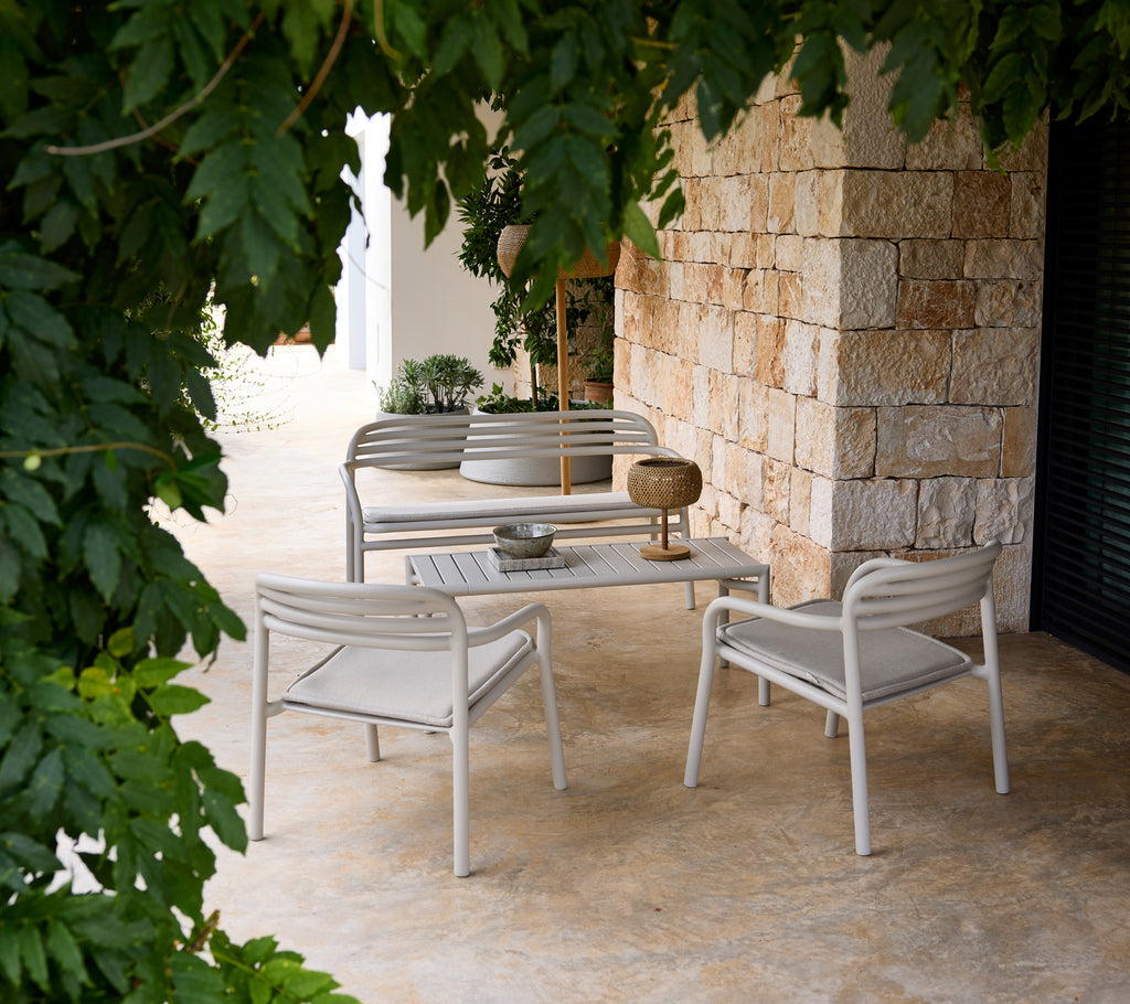 Grå soffa och stol med ett vitt bord i en modern loungeinställning.