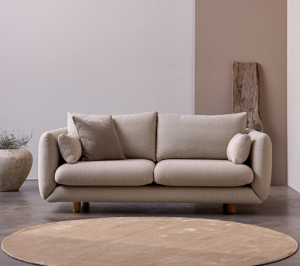 Bloom 2-sitssoffa med teakben i färgen Desert Sand, med mjuka kuddar och en mjuk, minimalistisk design.