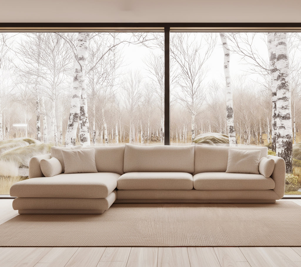 Beige modern soffa i en ljus loungeinställning med stora fönster.