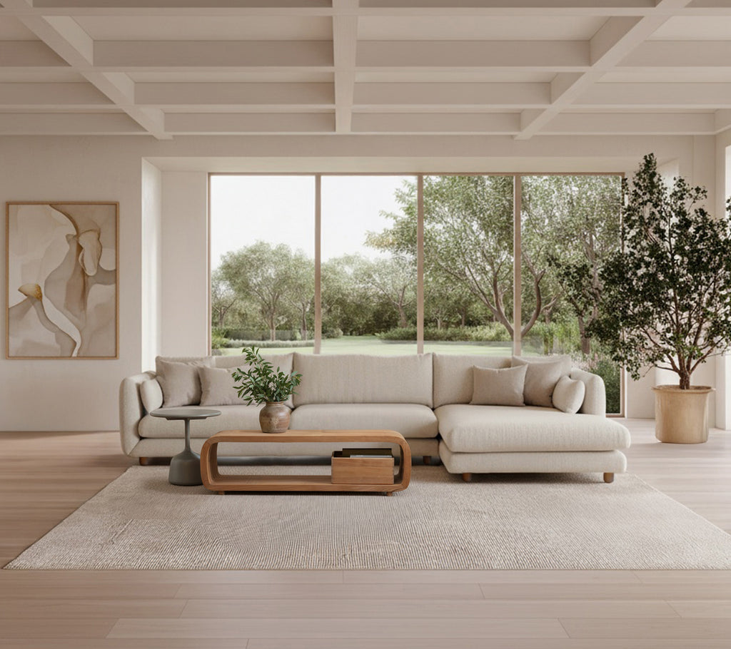 Modern lounge med en beige soffa, ett träkaffebord och en grön växt.