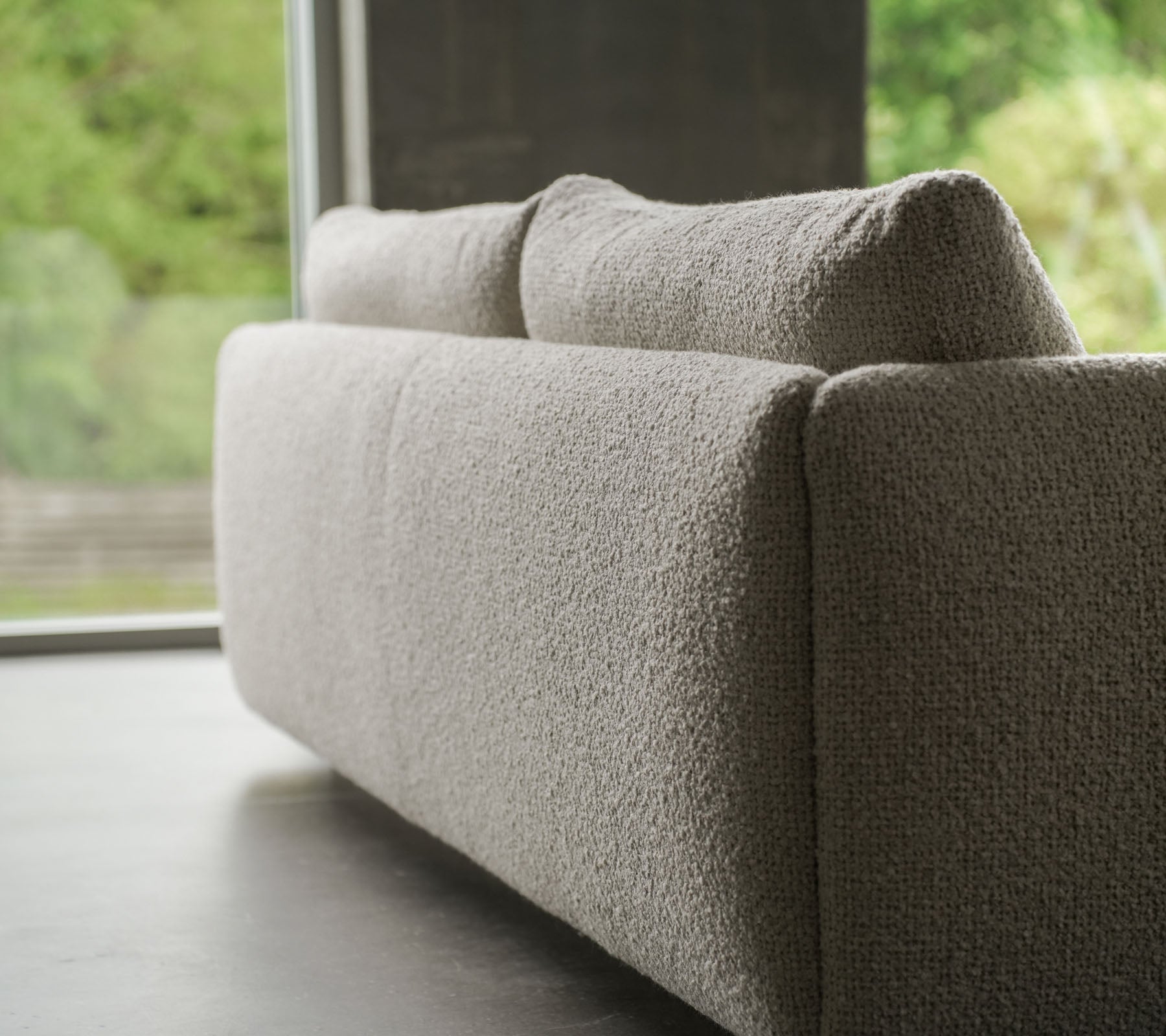 Samtida soffa med ett texturerat sandfärgat tyg, accentuerad av eleganta ben i teak, som visar Cane-line stil och mjuka kuddar.
