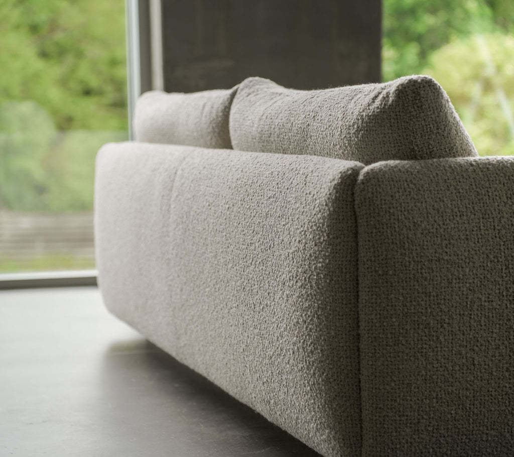 Samtida soffa med ett texturerat sandfärgat tyg, accentuerad av eleganta ben i teak, som visar Cane-line stil och mjuka kuddar.