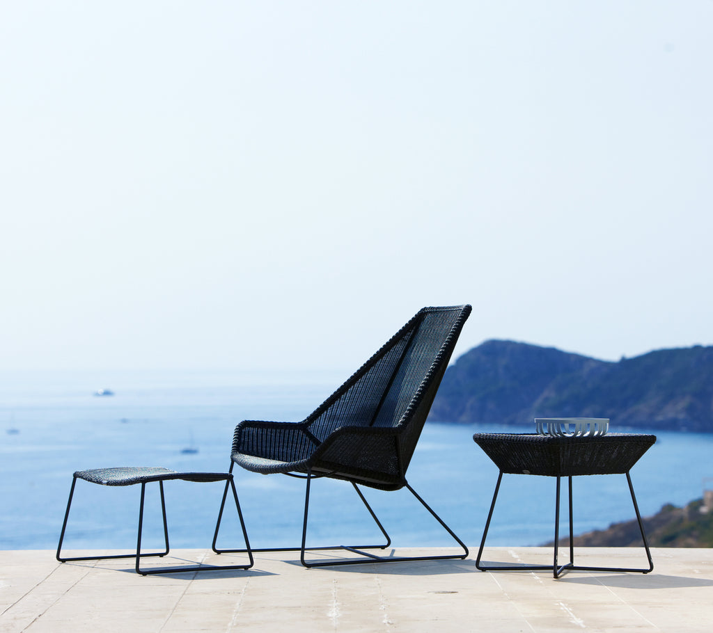 Modern svart stol och bord med utsikt över havet.