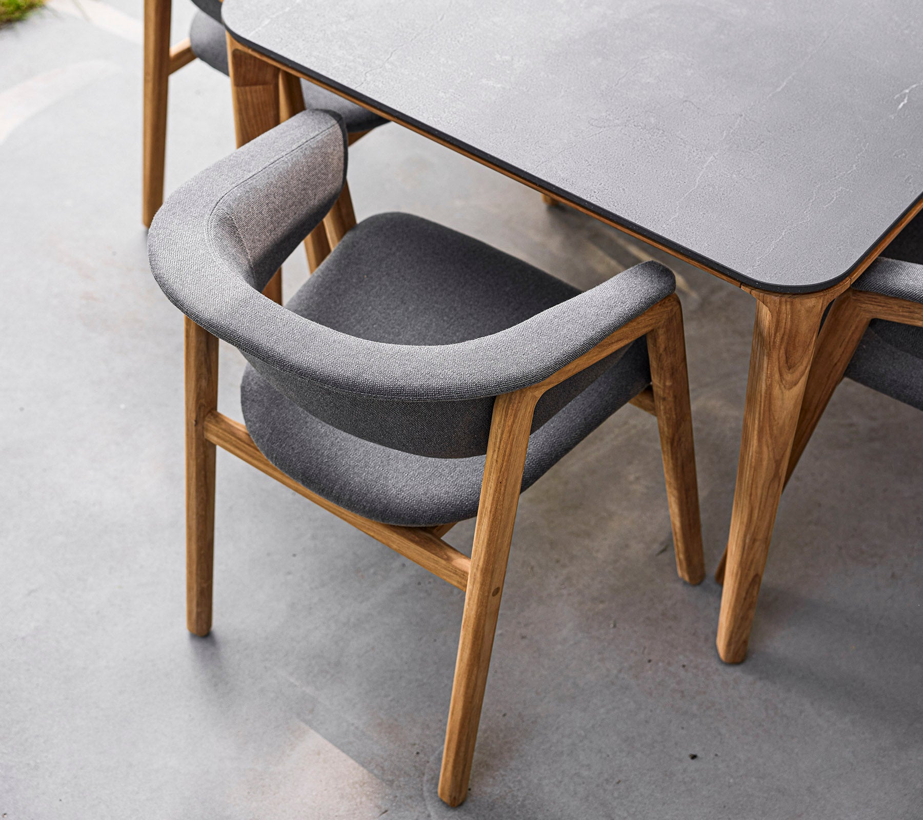 Stilfull stol med trästomme och mjuk grå klädsel, designad för komfort och elegans. Perfekt för moderna matsalar.