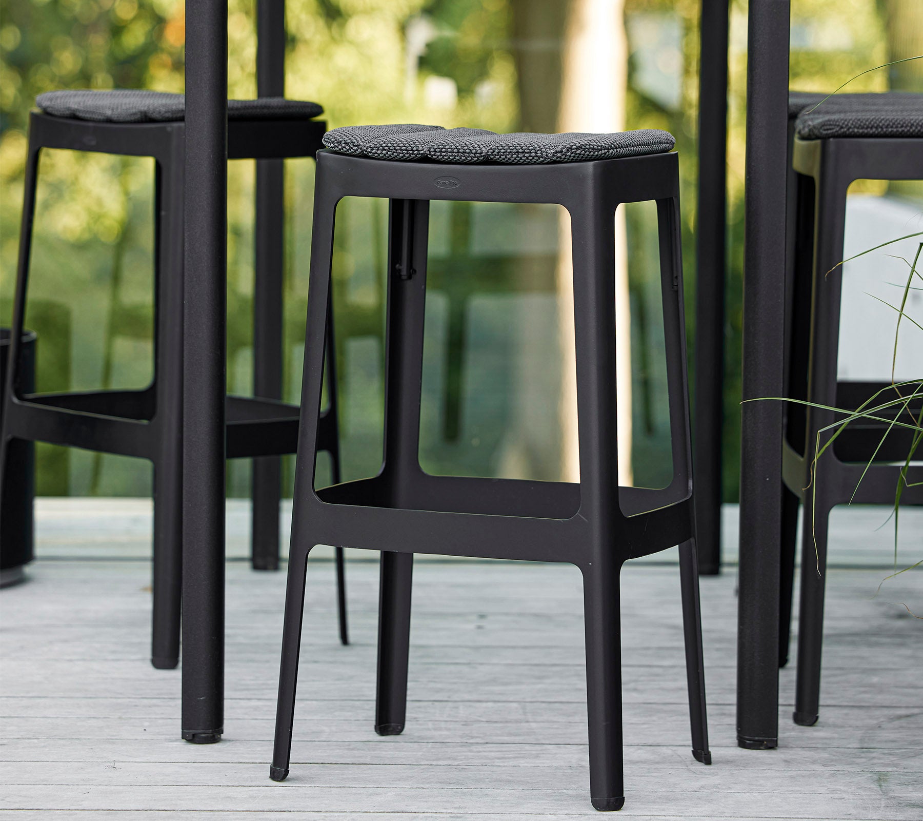 Svarta barstolar med minimalistisk design och vadderade säten, placerade tätt tillsammans och visar en modern estetik.