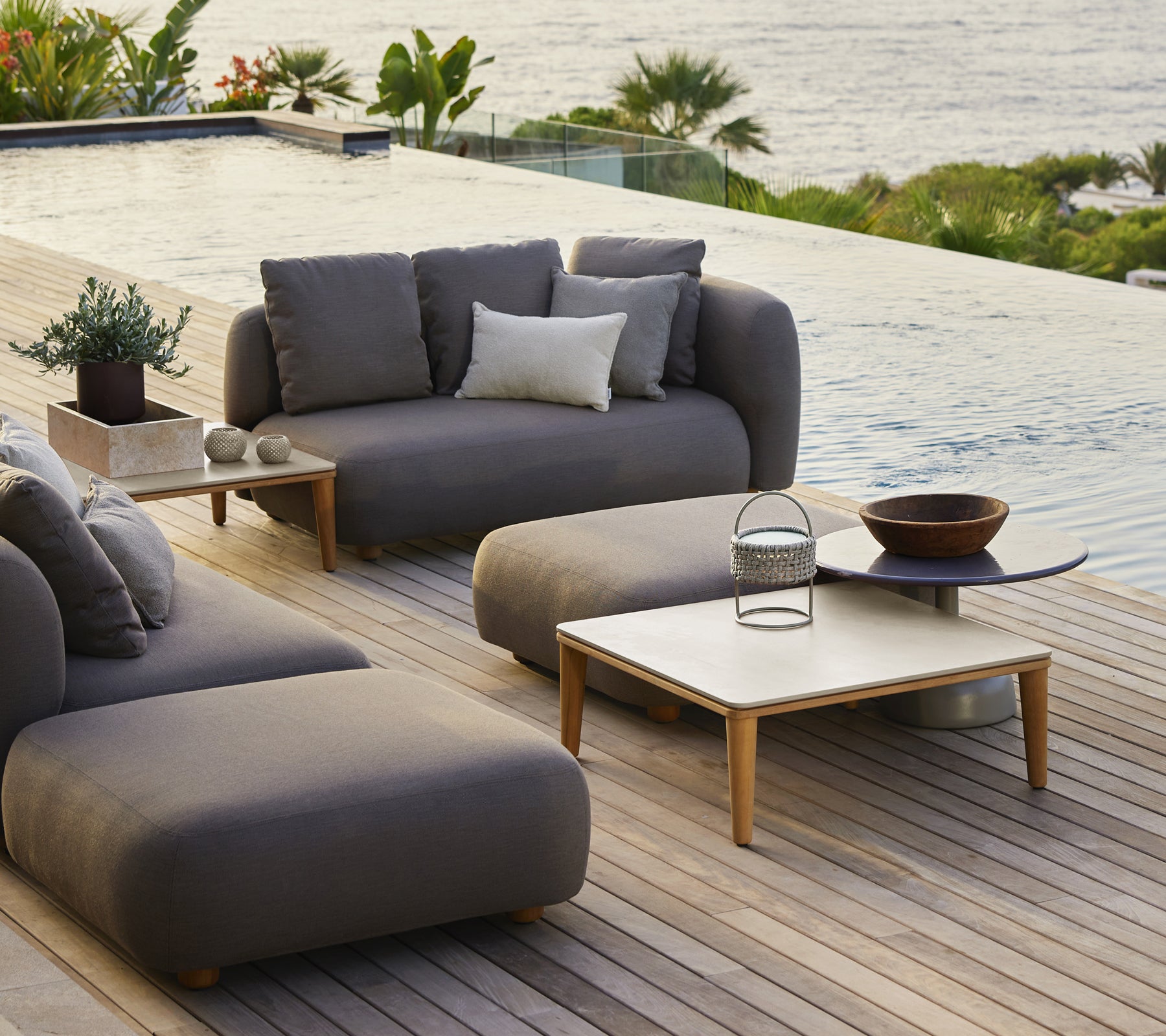 Modern utomhus loungemöbler med grå soffa, stol och träkaffebord.