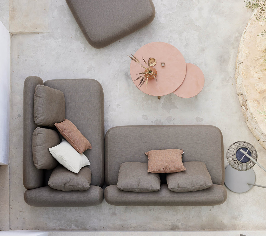 En stilren sittgrupp med en neutralfärgad soffa med dekorativa kuddar, tillsammans med ett unikt twist-bord.