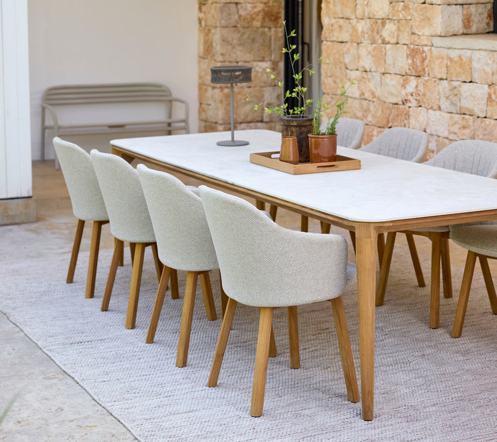 Modern matplats med ett vitt bord och beige stolar.