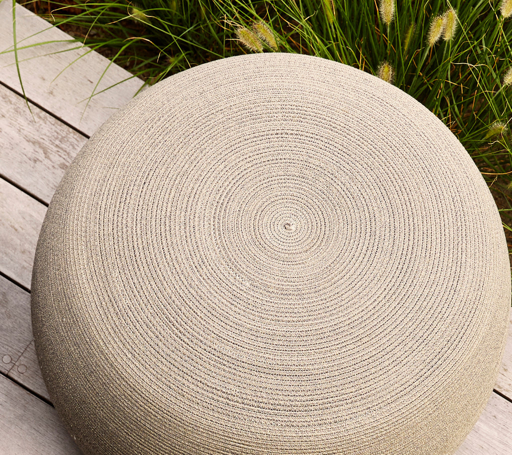 Rund taupe fotpall med en texturerad yta som har spiralmönster, perfekt för mångsidig sittplats eller dekoration.
