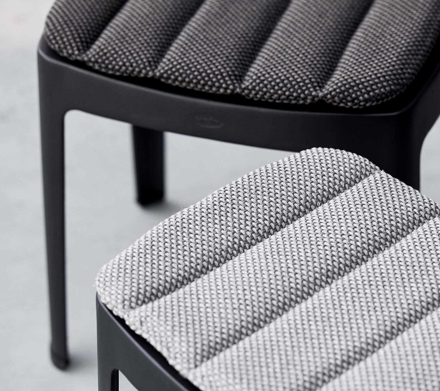Två stiliga pallar med texturerat tyg i kontrasterande grånyanser, som visar en modern design med släta linjer.