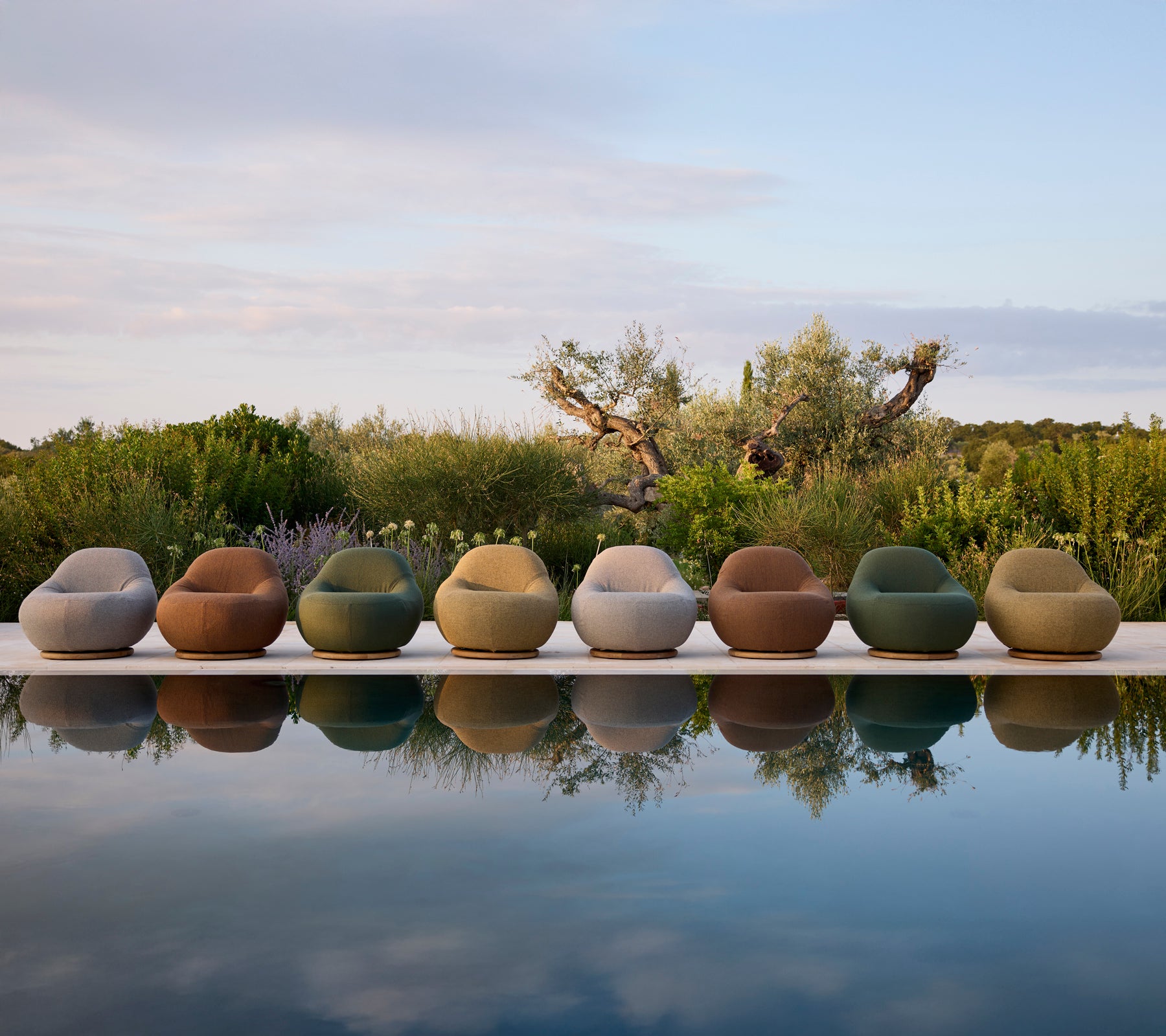 Samtida utemöbler i olika färger arrangerade vid poolkanten.