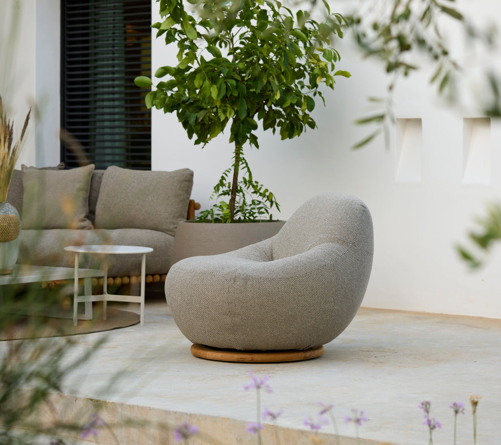 Modern loungemiljö med en grå stol, grå kudde och vitt bord.