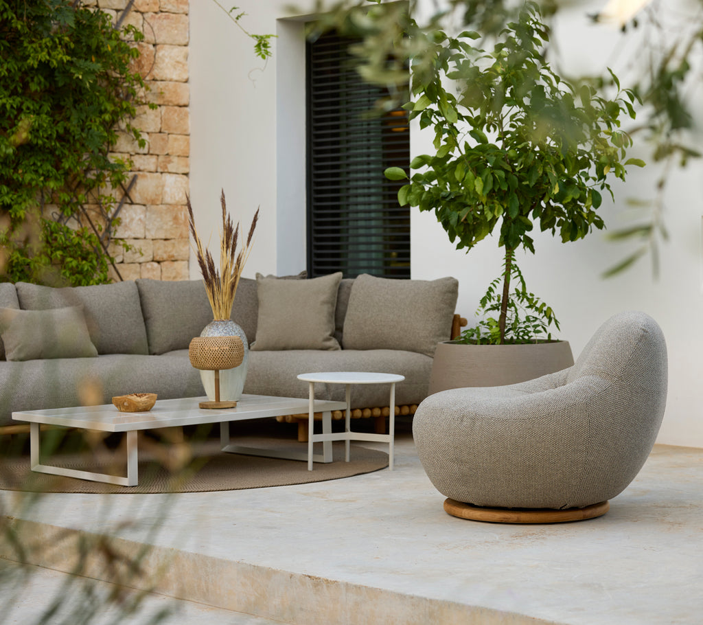 Modernt loungeområde med en grå sektionsoffa, vitt soffbord och rund stol.