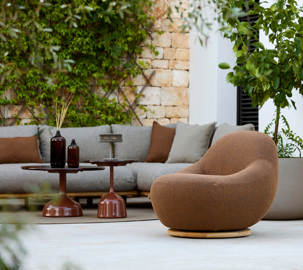 Modern loungedel med en brun fåtölj, grå soffa och ett brunt sidobord.