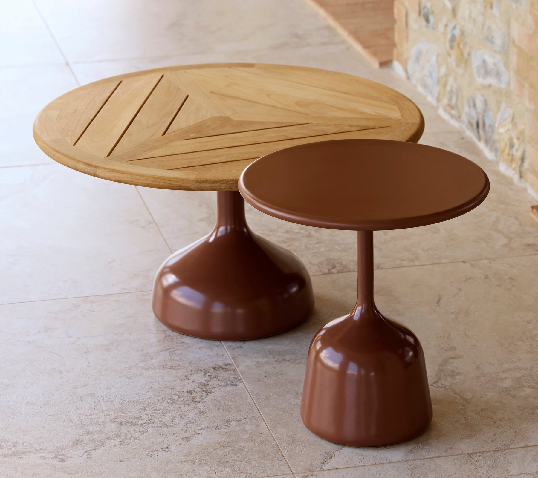 Två soffbord, ett med en träskiva och geometrisk design, det andra med en slät, ökenröd finish, som delar en modern estetik.