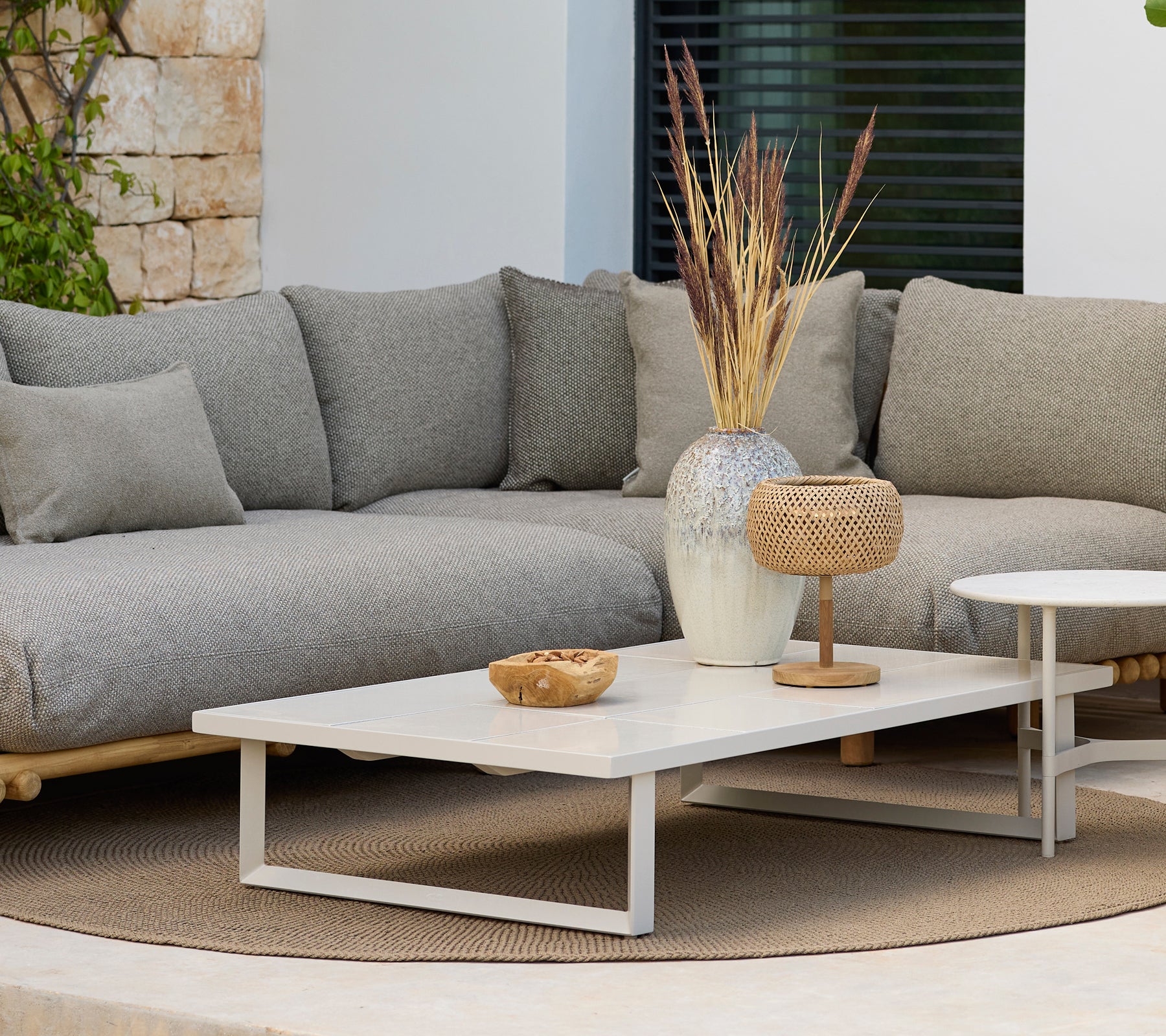 Moderna loungeområde med en grå soffa och ett vitt kaffebord med dekoration.