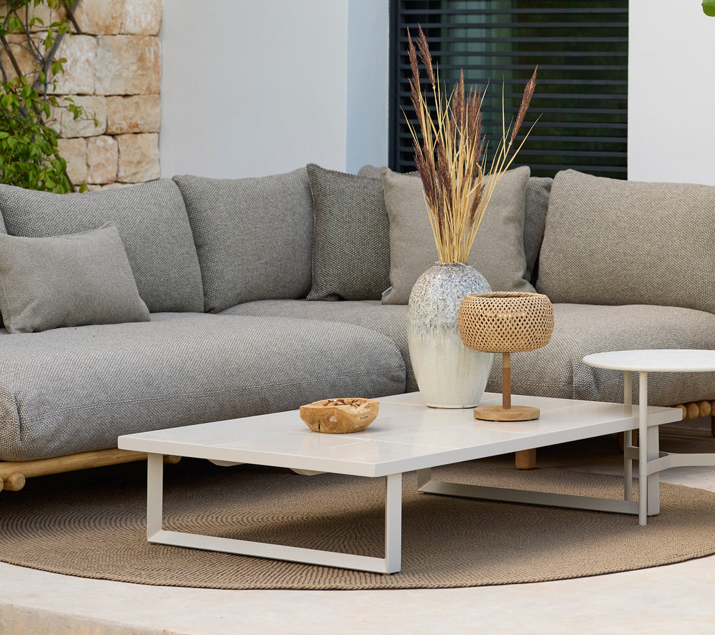 Moderna loungeområde med en grå soffa och ett vitt kaffebord med dekoration.