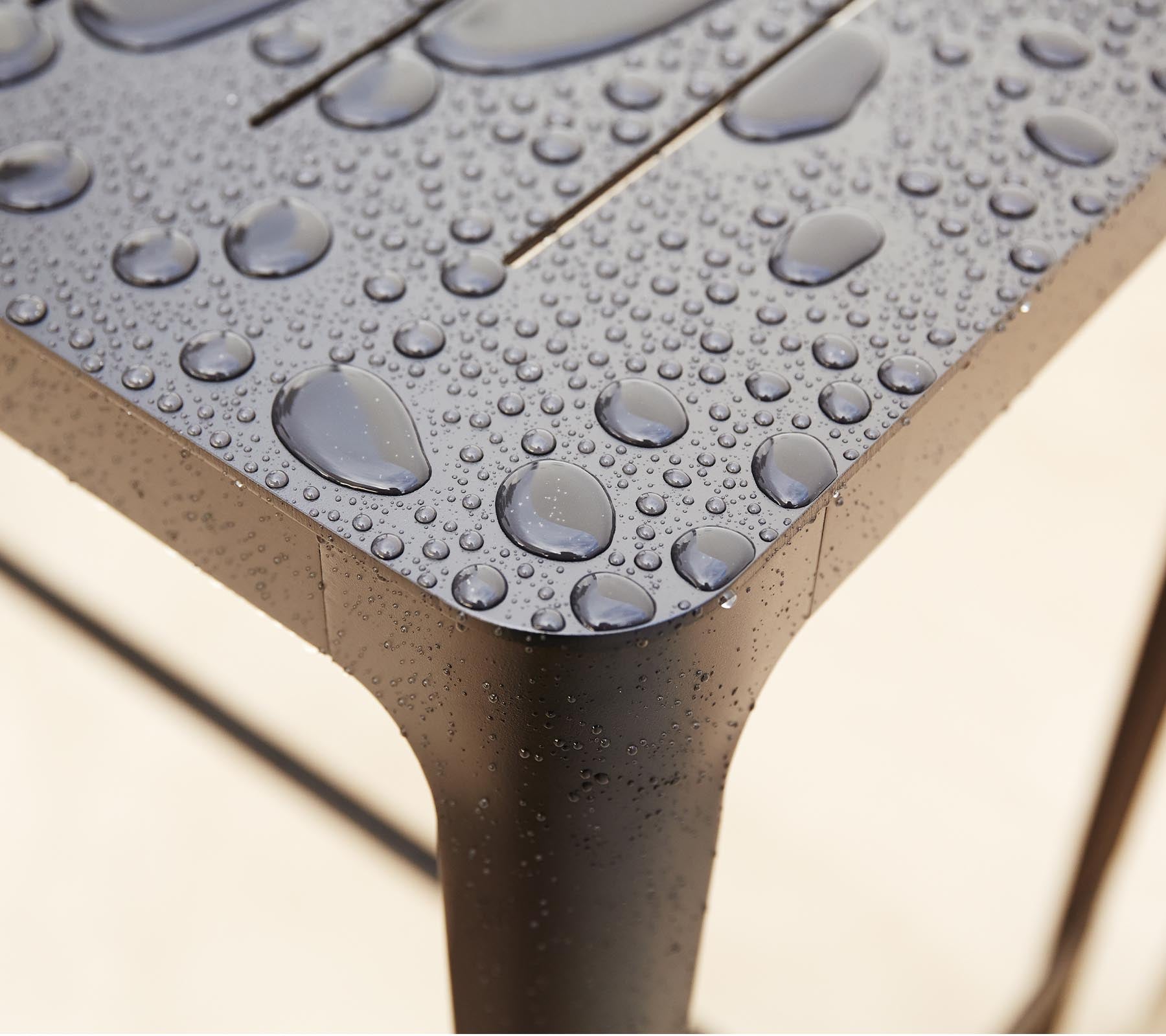 Närbild av en strukturerad yta med vattendroppar, som framhäver den eleganta designen och detaljerna i materialet.
