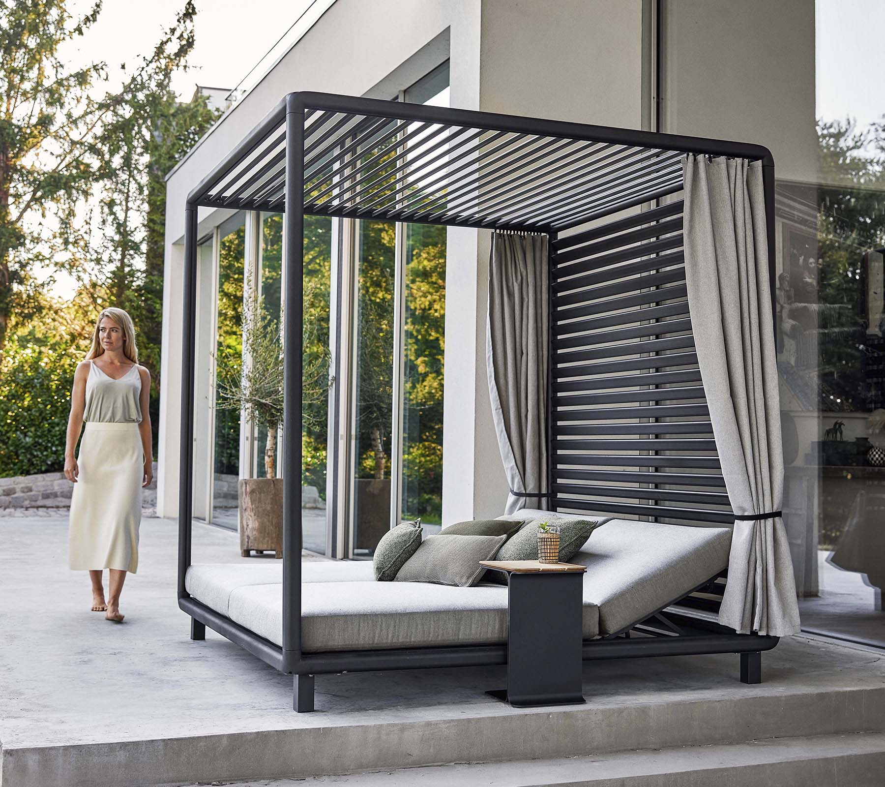 En stilren cabana med modern design, som har ett bekvämt loungeområde och mjuka gardiner, belägen i en lugn miljö.