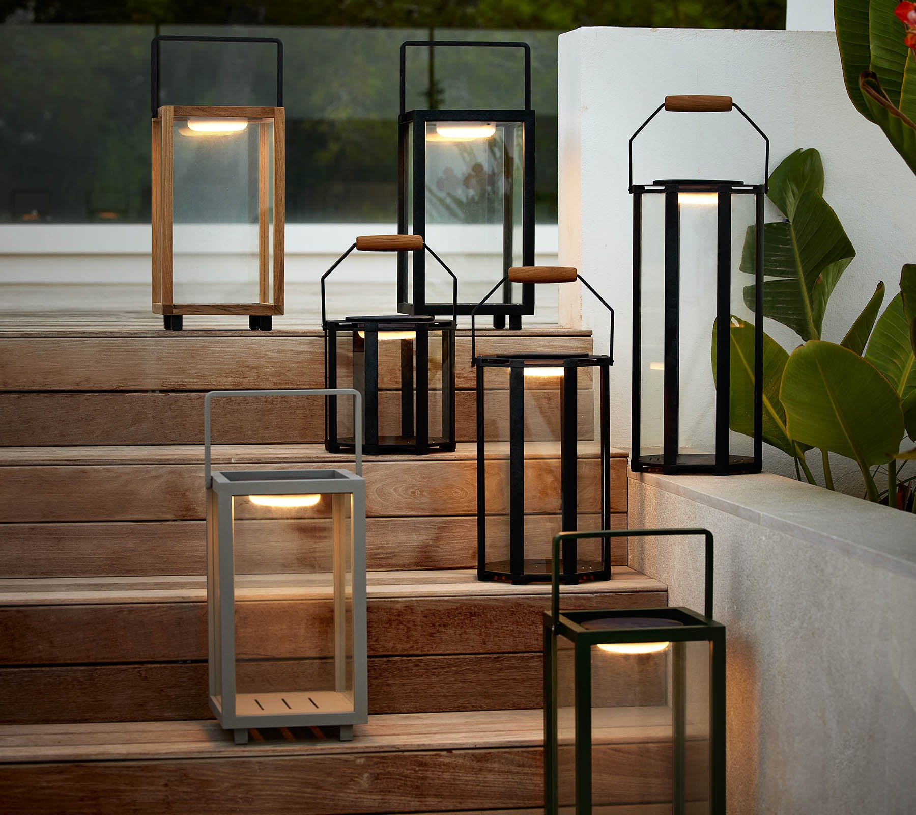 En samling moderna lyktor i olika stilar och färger, arrangerade på en trappa, som framhäver deras eleganta design och varma belysning.