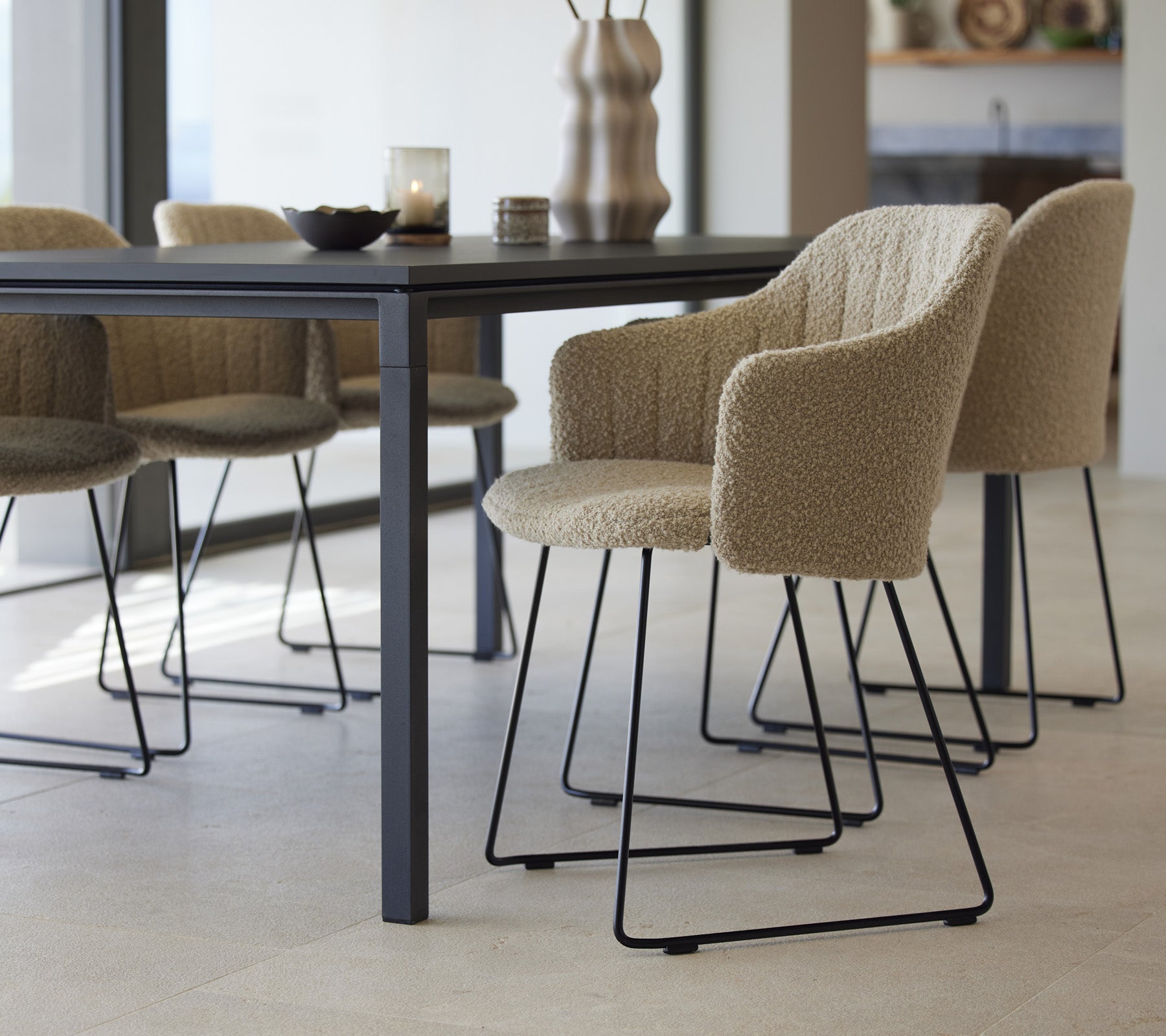 Ett stiligt matbord med texturerade stolar, som har en modern design och minimalistiska element, dukat för en inbjudande matupplevelse.