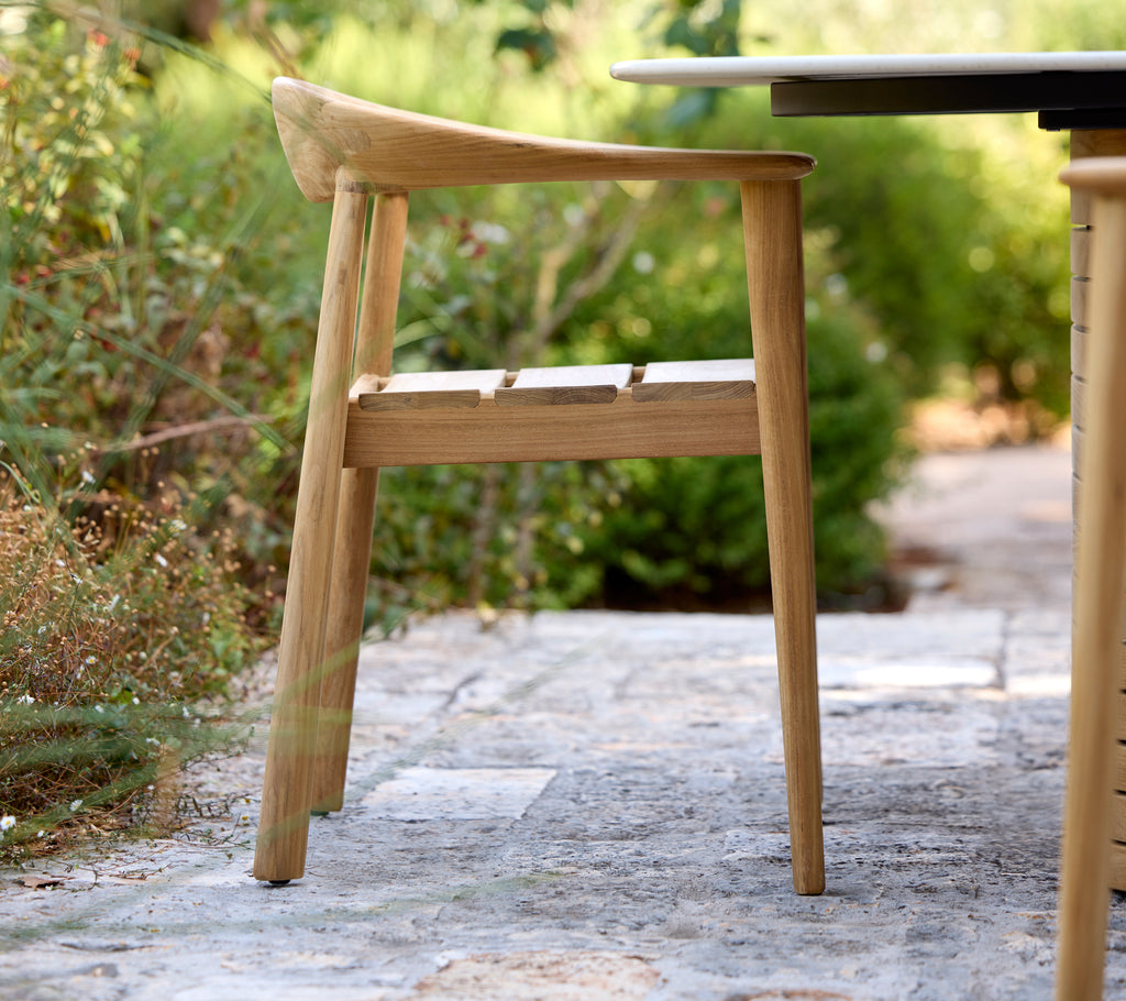 Modern trästol vid ett svart bord i en utomhusmiljö.