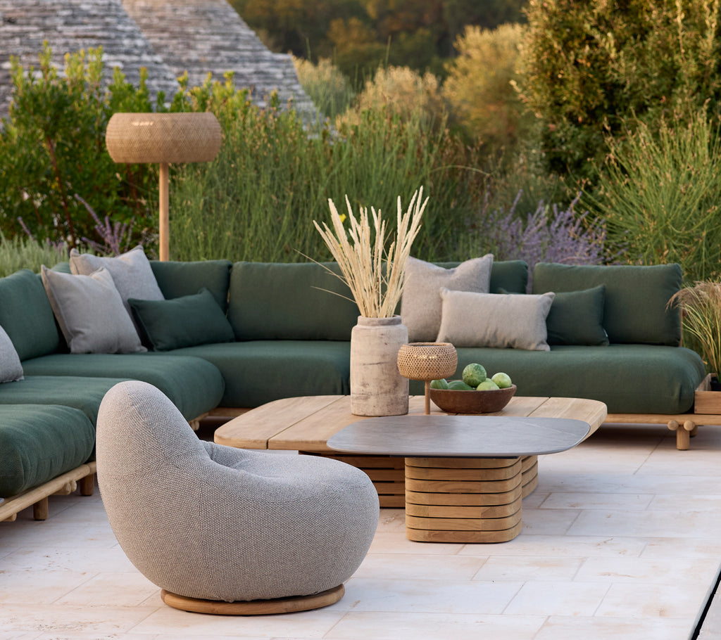 Moderna loungeområdet med en grön soffa, grå stol och runt soffbord.