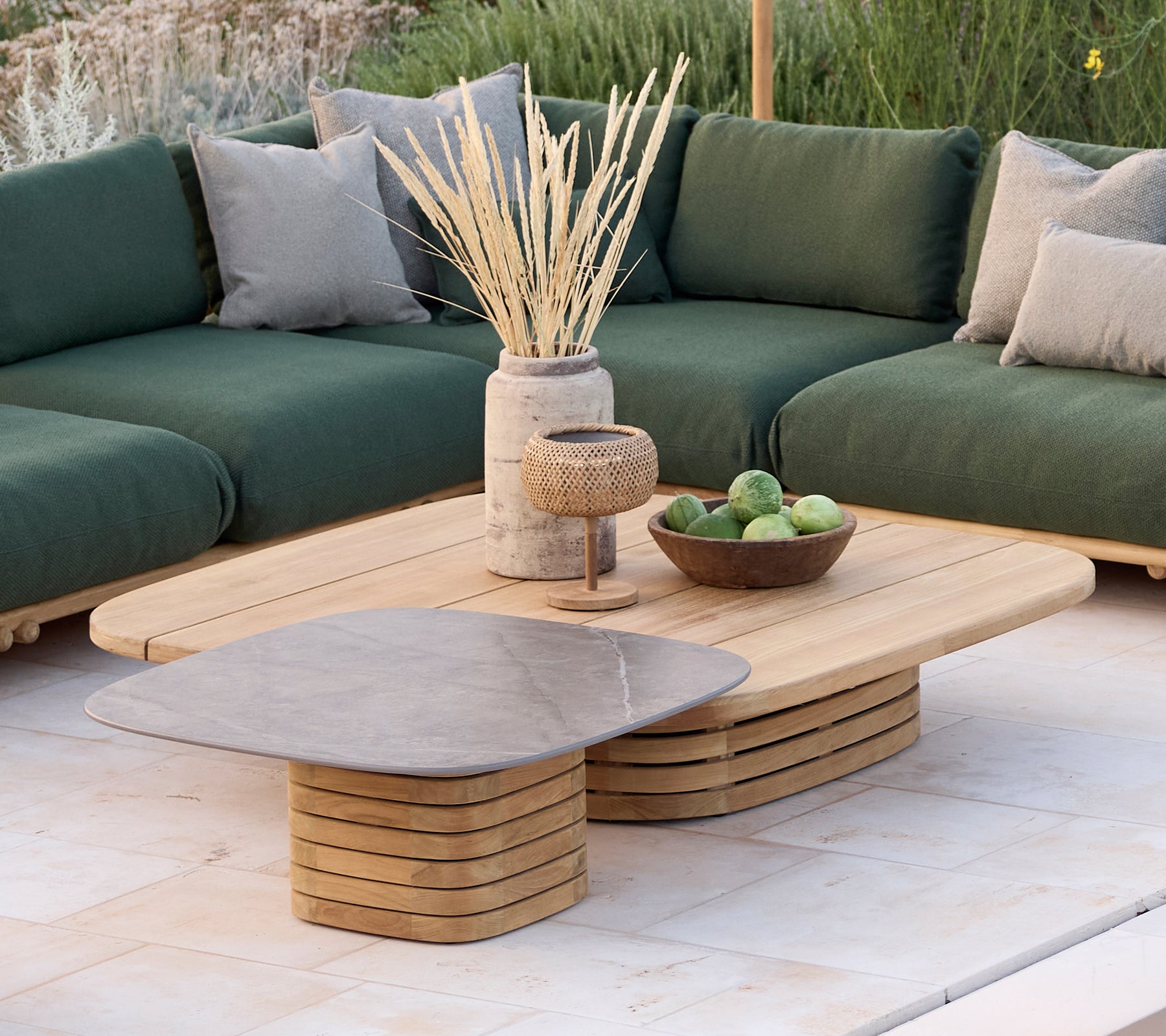 Modernt loungeområde med en grön soffa med kuddar, ett träkaffebord och dekorativa föremål.