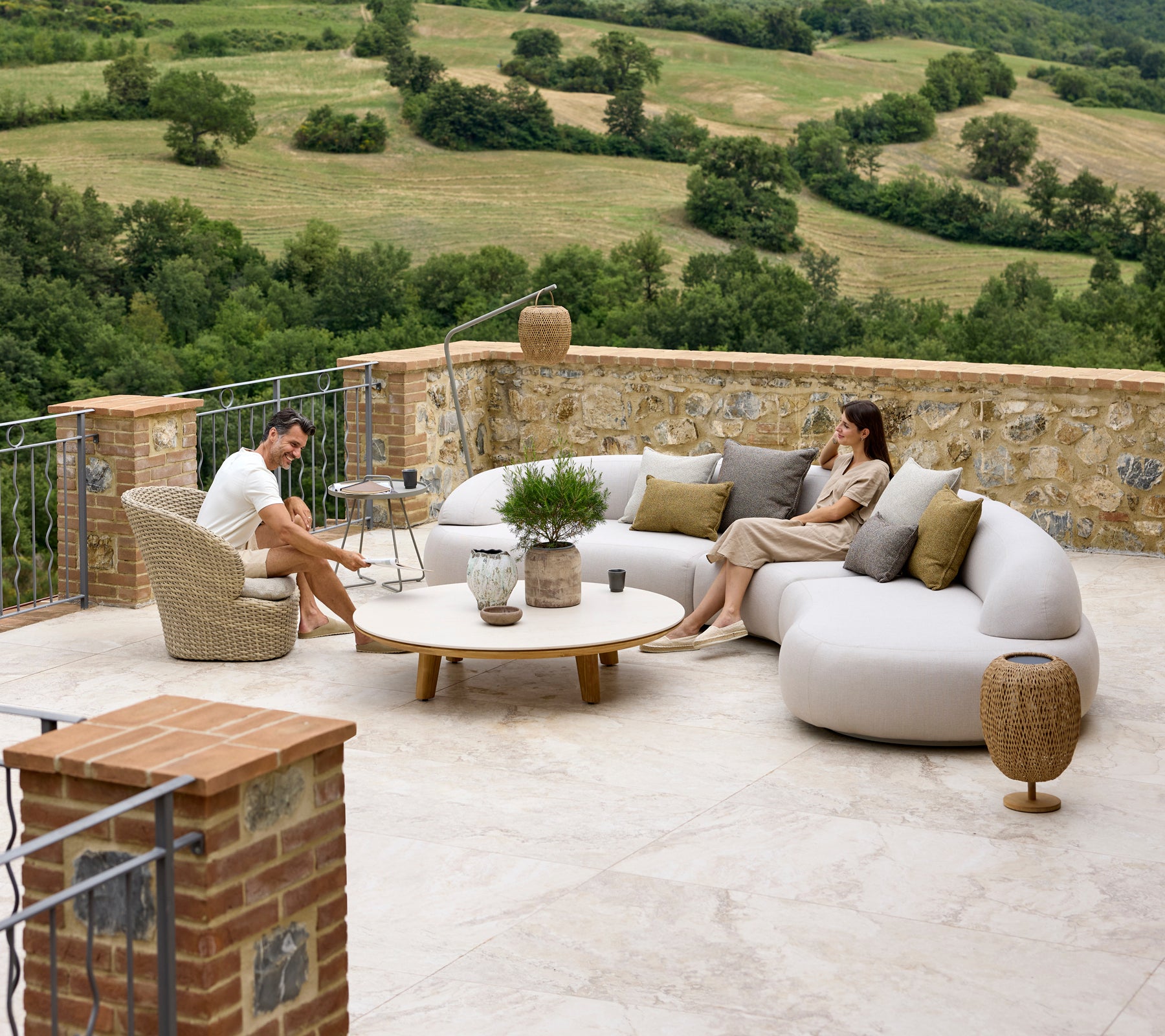 Avslappnande sittarrangemang med en mjuk lounge-soffa, Coast-lounge stol, Aspect kaffebord och Illusion Glow detaljer med en naturskön bakgrund.