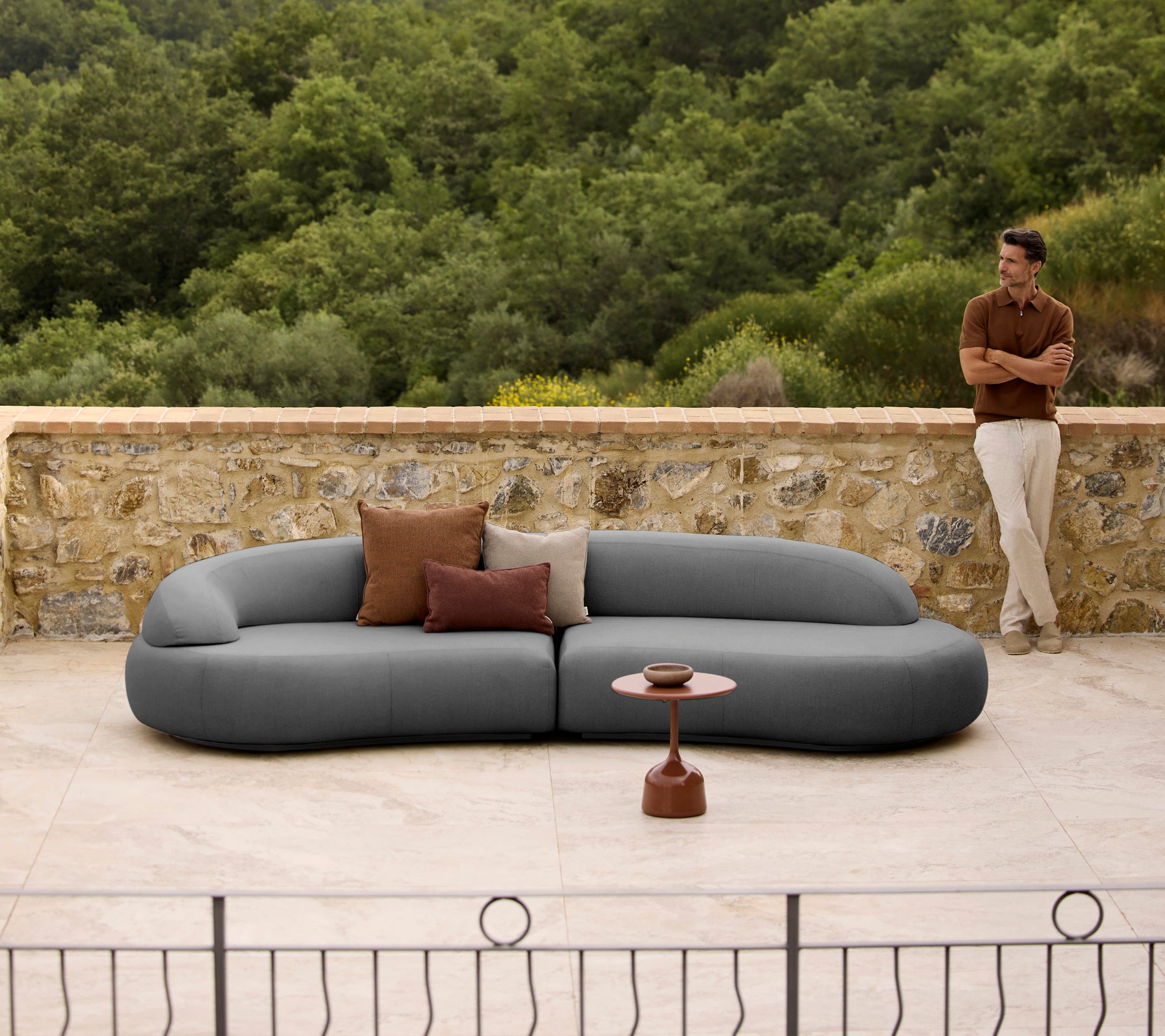 Mellow lounge-soffa med kuddar bredvid ett stiligt Glaze soffbord, mot en naturlig bakgrund.