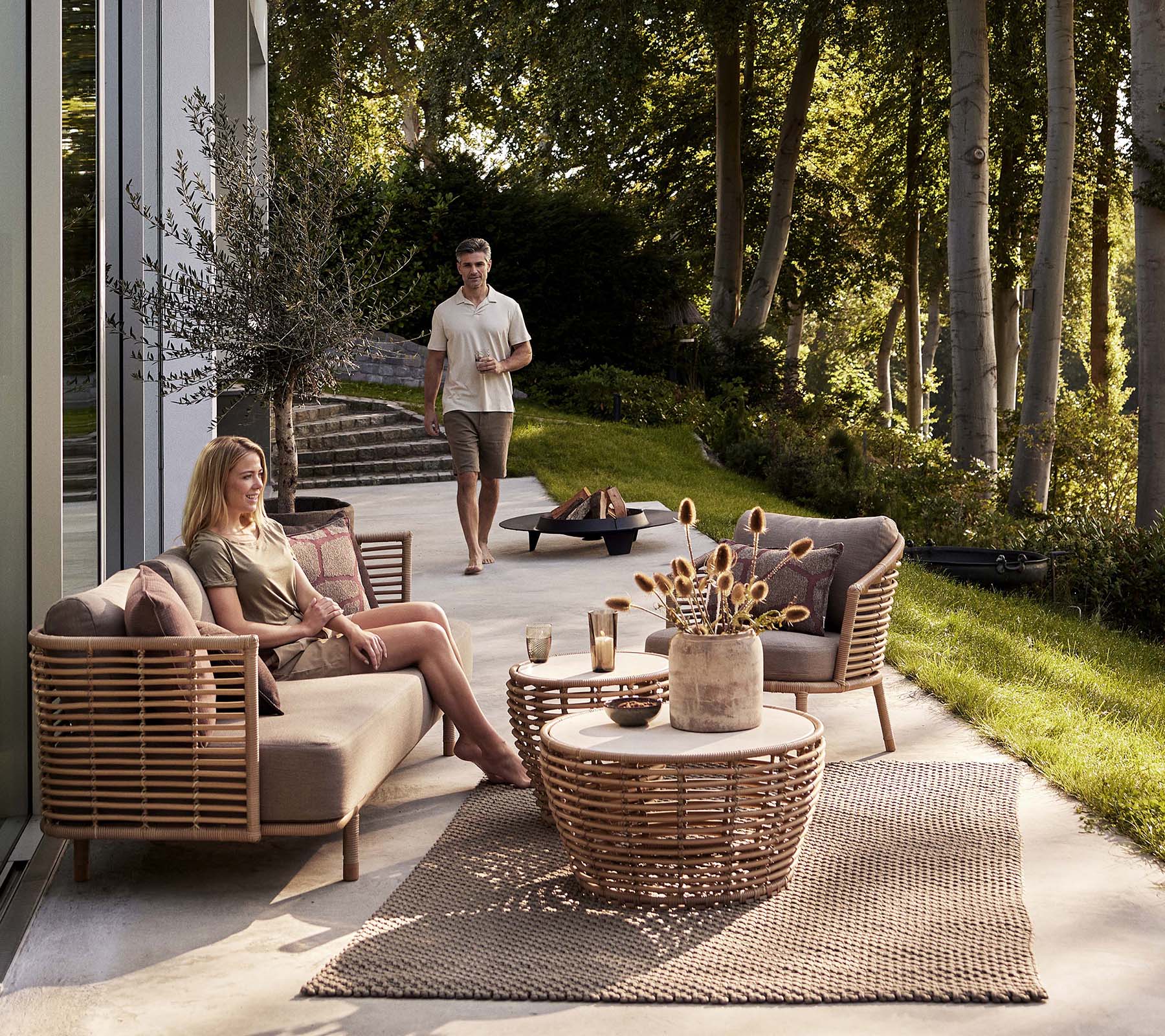 En mysig sittgrupp med en Sense-soffa och en fåtölj, kompletterad med ett korgkaffebord och dekorativa element.