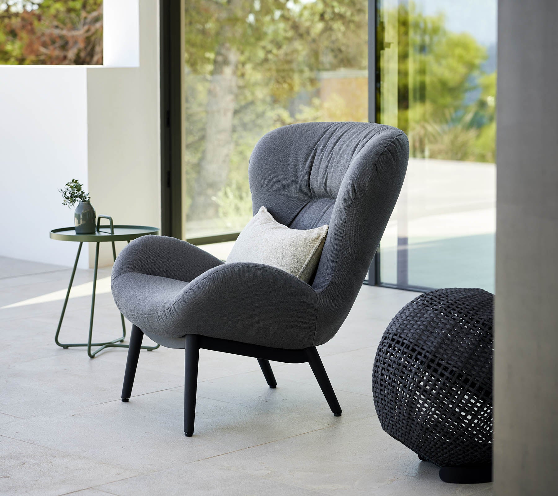 en lugn loungestol med modern design, som har mjuk stoppning och eleganta ben, åtföljd av ett litet sidobord och dekorativa detaljer.