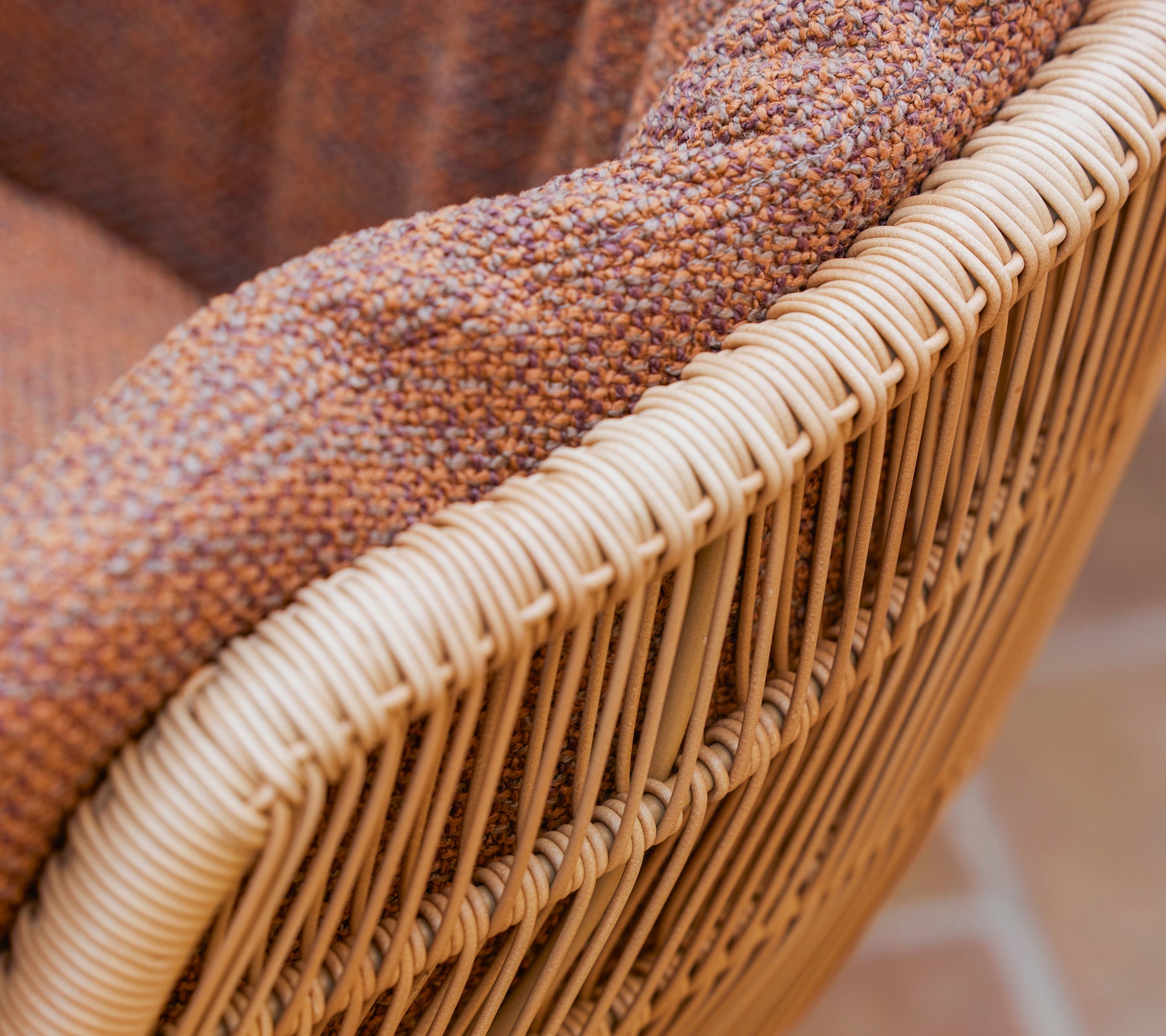 Närbild av en Stay matstol med en texturerad brun Rise-kudde och en vävd ram av naturliga fibrer.