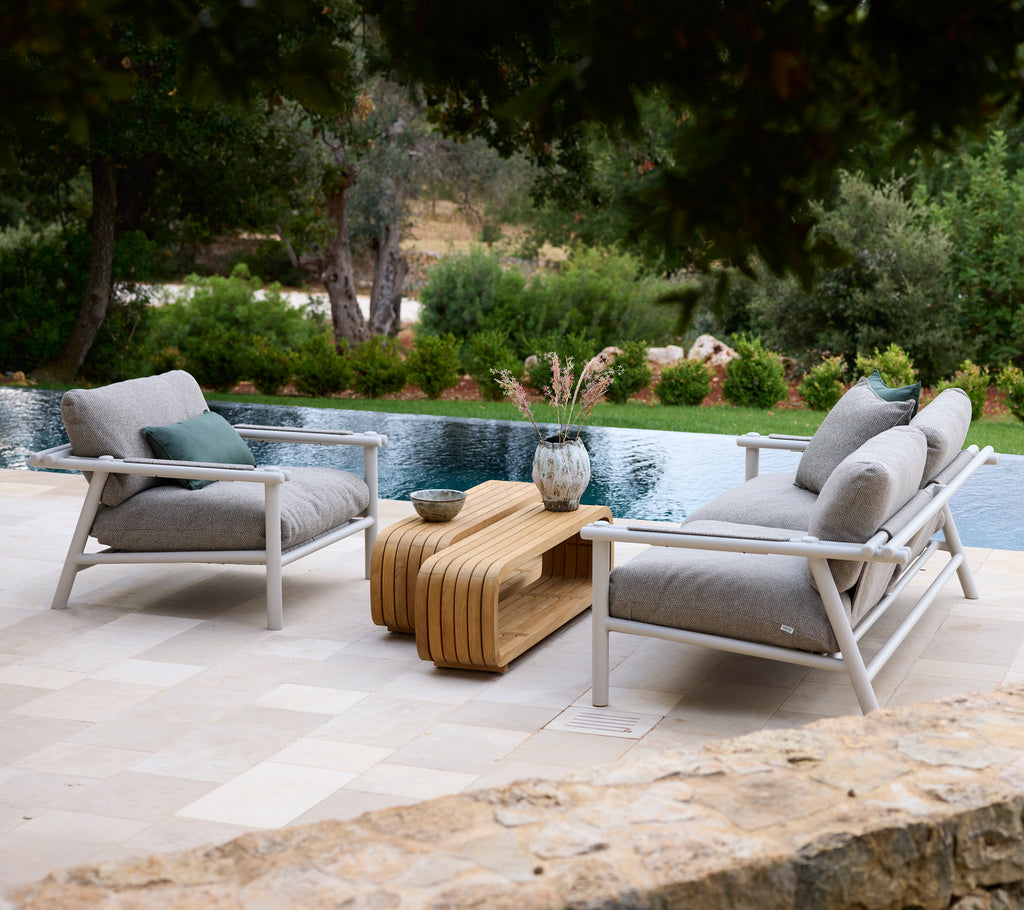 Modernt loungeområde med vita stolar med grå kuddar och ett träkaffe bord.